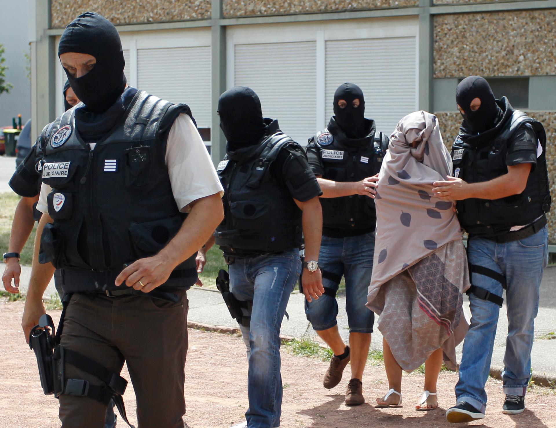 French special Police forces escort a woman from a residential building during a raid in Saint-Priest, near Lyon, France, June 26, 2015.