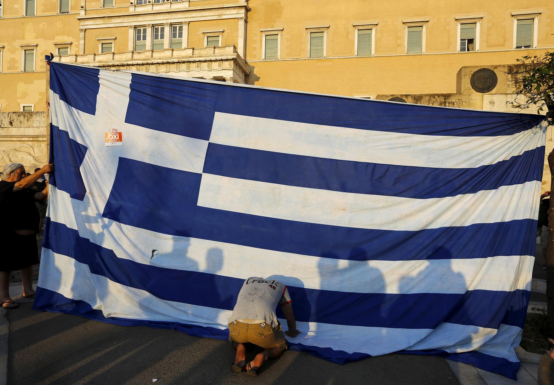 Protester kneels before Greek flag at protest in Athens
