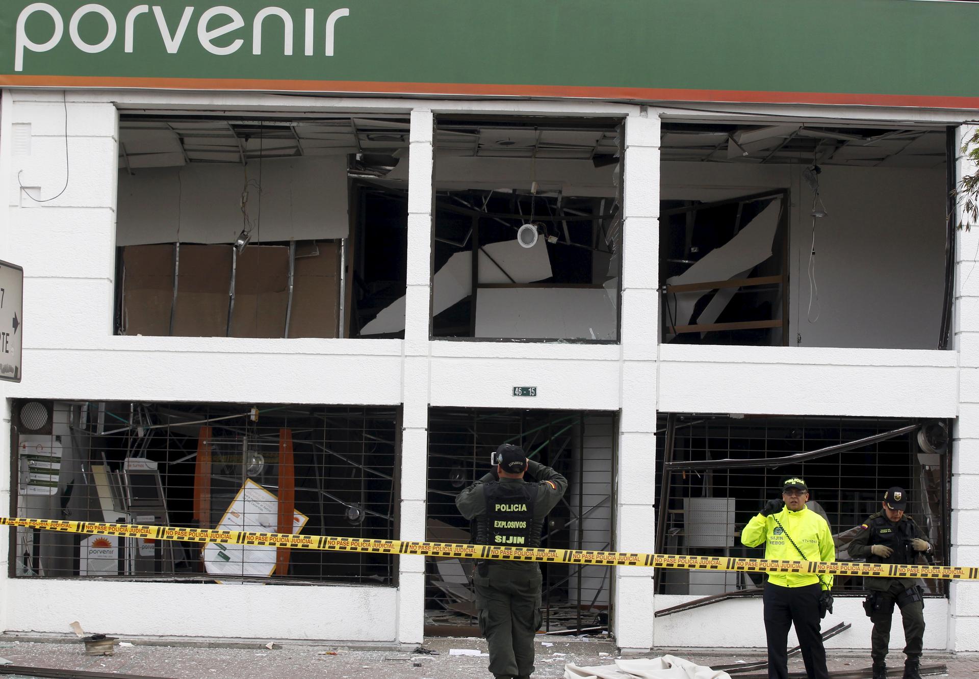 Police examine a bombed-out office in Bogota's financial district