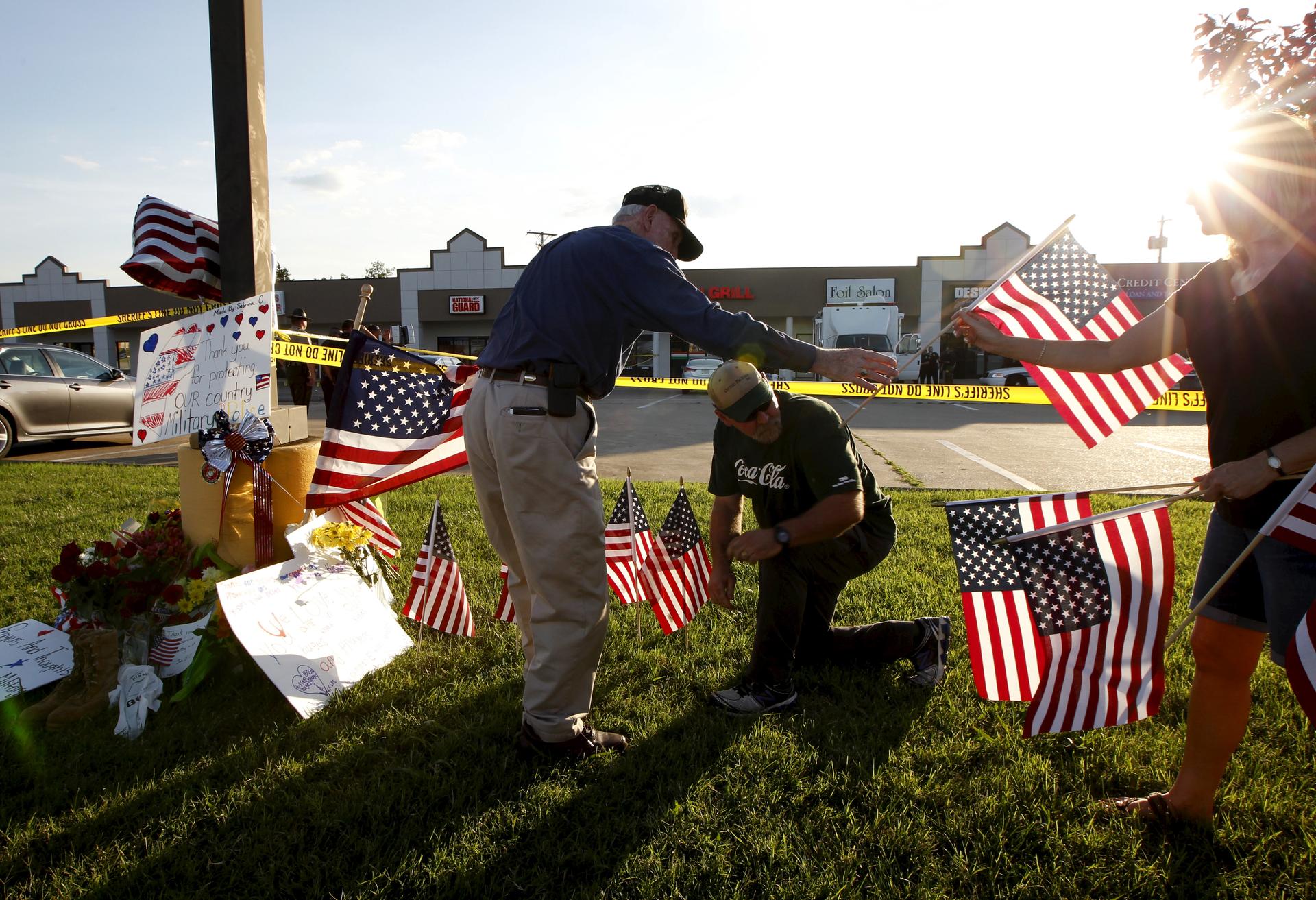 Mourners places flags at a growing memorial in front of the Armed Forces Career Center in Chattanooga, Tennessee on July 16, 2015. Four Marines were killed on Thursday by a gunman who opened fire at two military offices in Chattanooga, Tennessee, before b