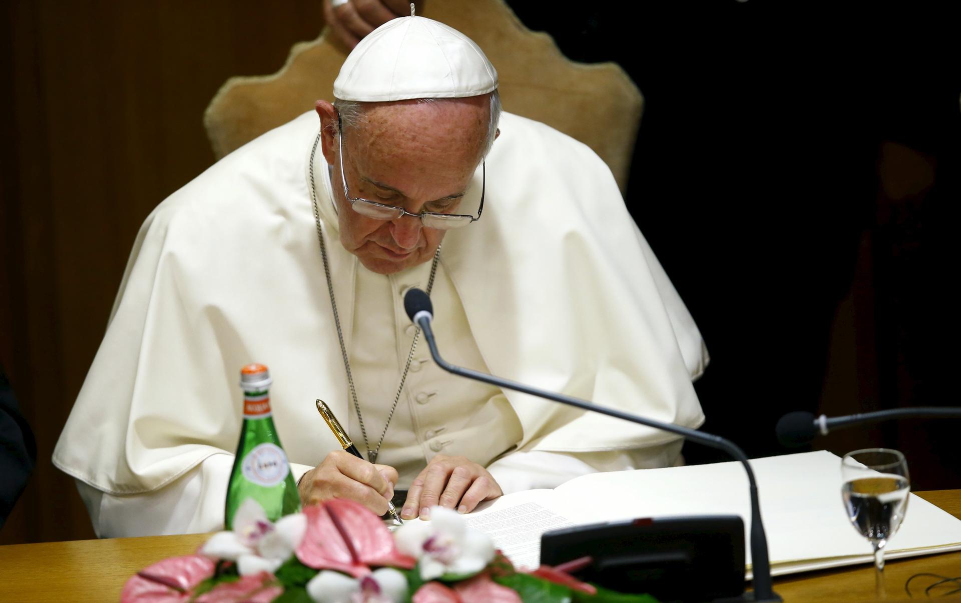 Pope Francis signs a declaration during the "Modern Slavery and Climate Change" conference