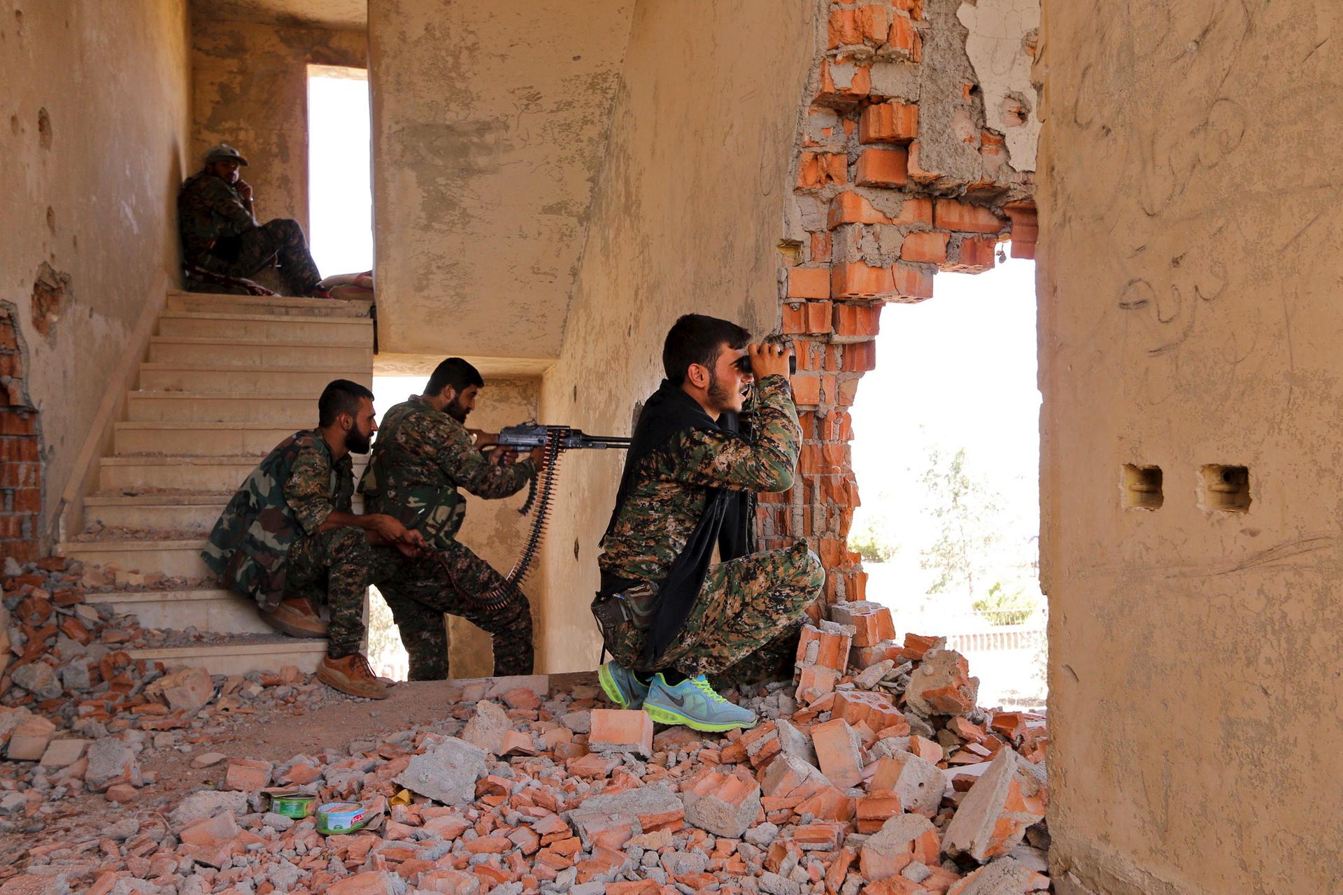 Kurdish People's Protection Units (YPG) fighters take up positions inside a damaged building in al-Vilat al-Homor neighborhood in Hasaka city, as they monitor the movements of Islamic State fighters who are stationed in Ghwayran neighborhood in Hasaka cit