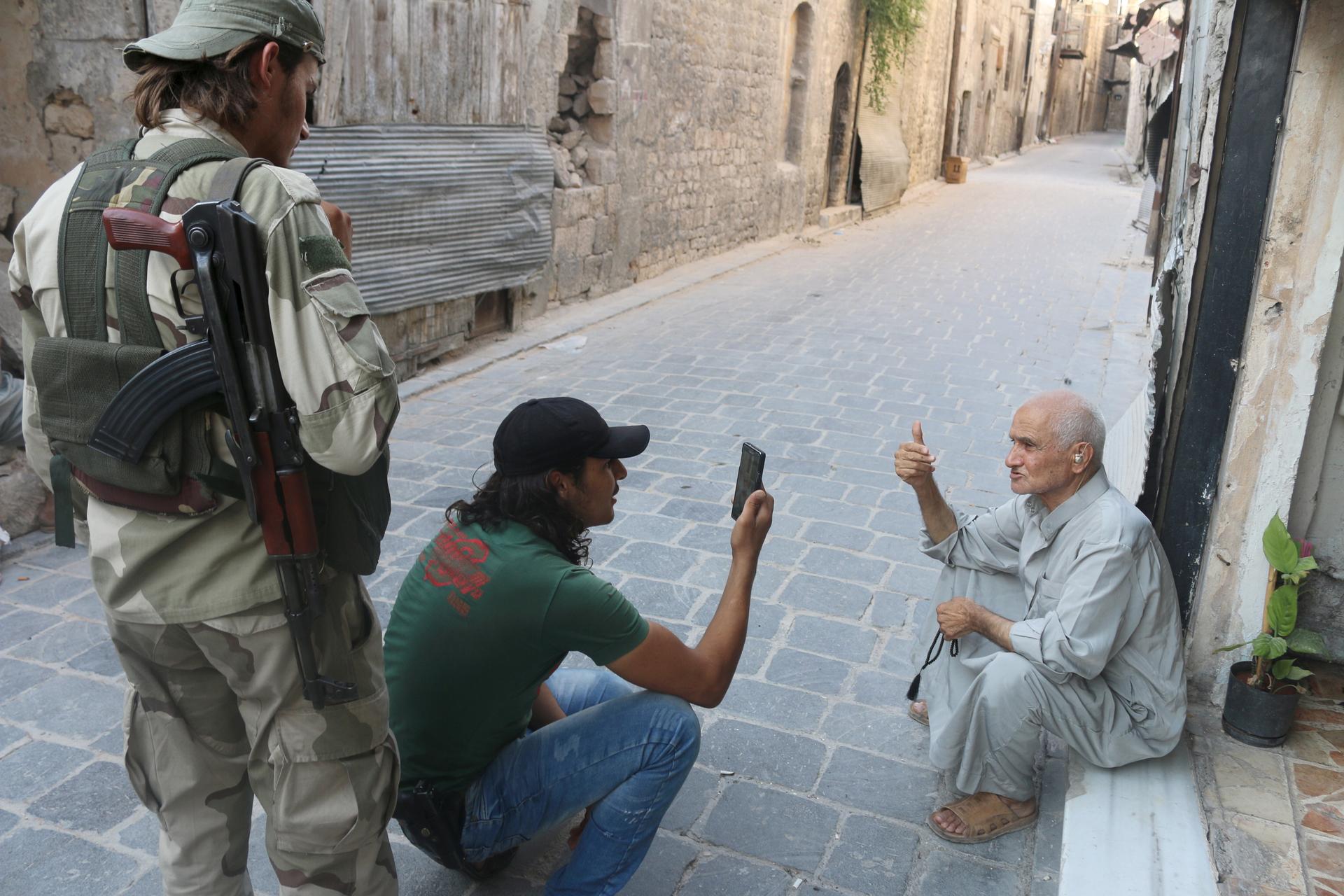  Free Syrian Army fighters snap a picture of an elderly man using a mobile phone in Old Aleppo, Syria. 