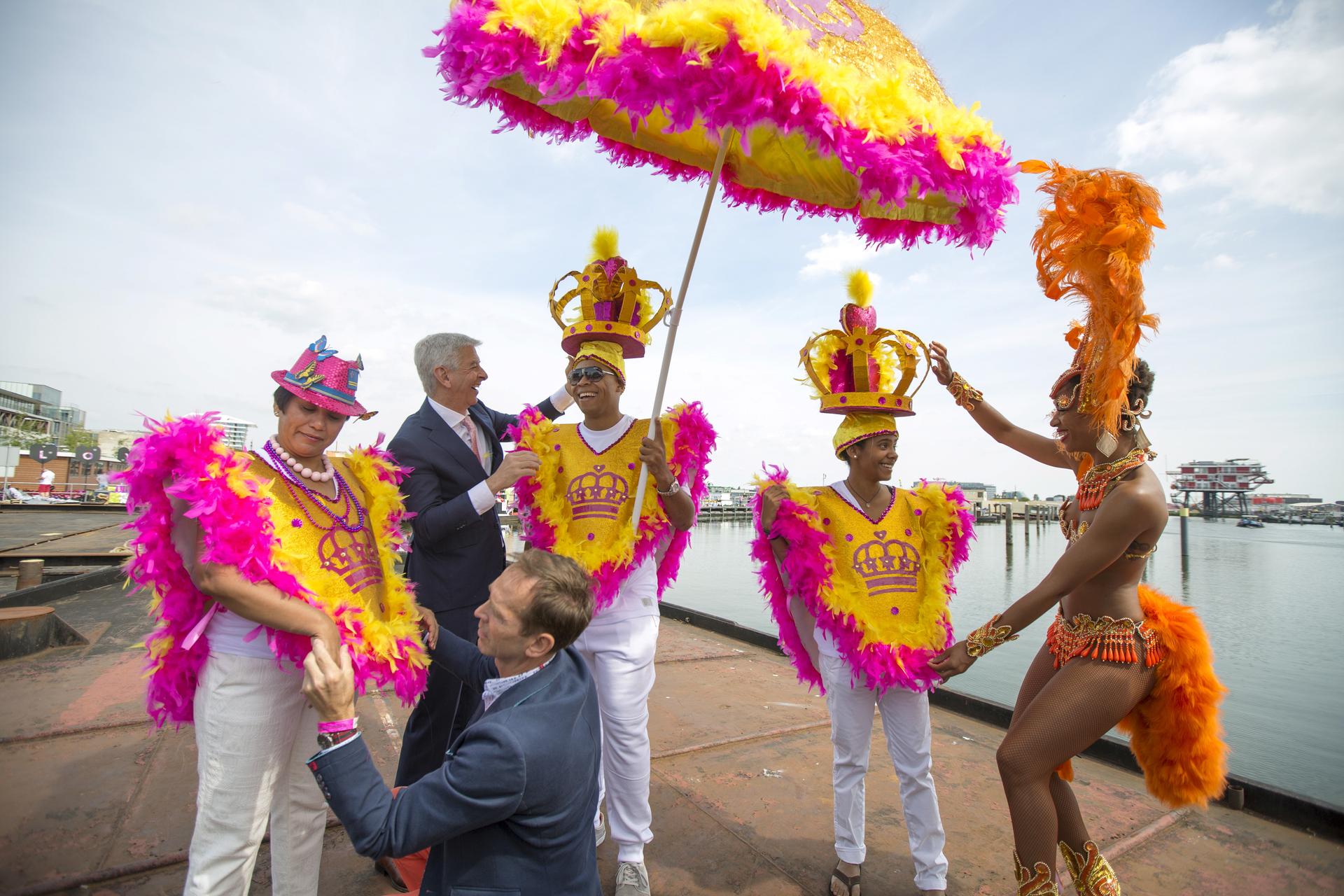 The Netherlands' Minister of Kingdom Relations Ronald Plasterk (2nd L, top) helps adjust costumes of participants from Curacao before their boat leaves for the festival's canal parade in Amsterdam, the Netherlands August 1, 2015.