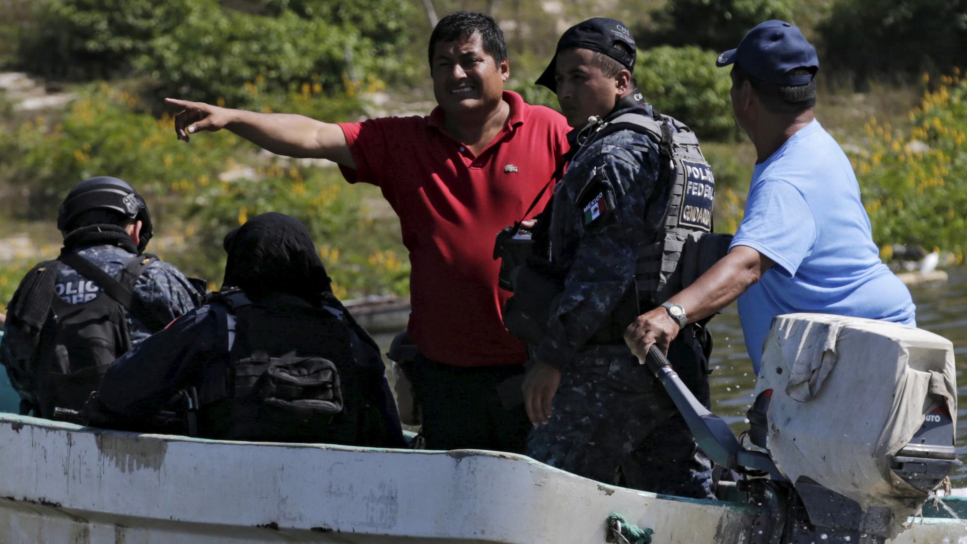 Miguel Angel Jimenez (in red), leader of the community police of Guerrero State (UPOEG), speaks with a federal police on a boat as they seek for the 43 Ayotzinapa students' missing, in Acatlan, in the southwestern state of Guerrero, October 30, 2014.