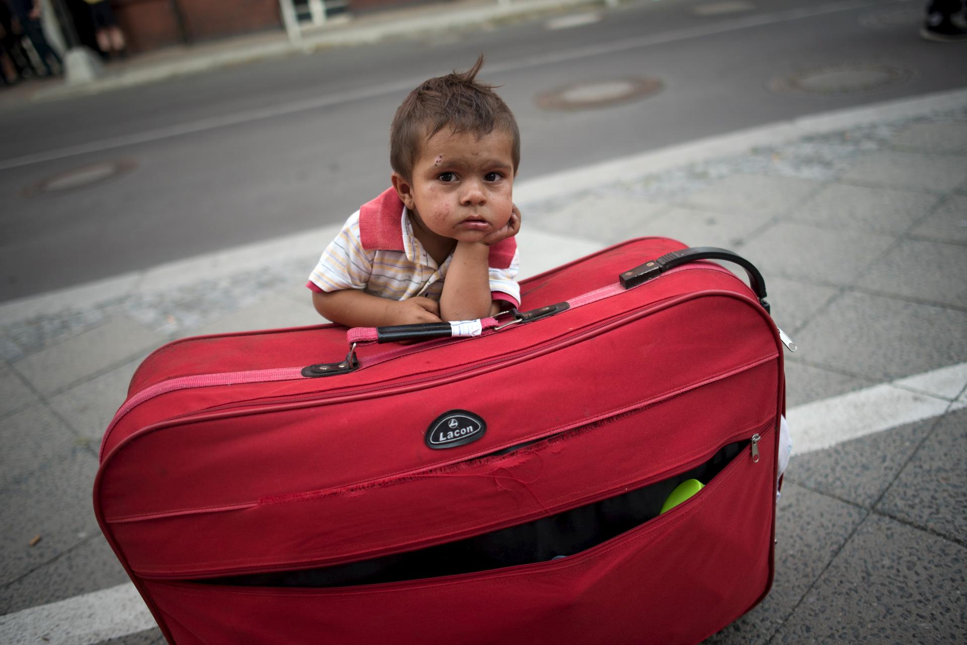 A migrant boy guards his parents' suitcase, as the family waits all day to apply for asylum in Berlin.