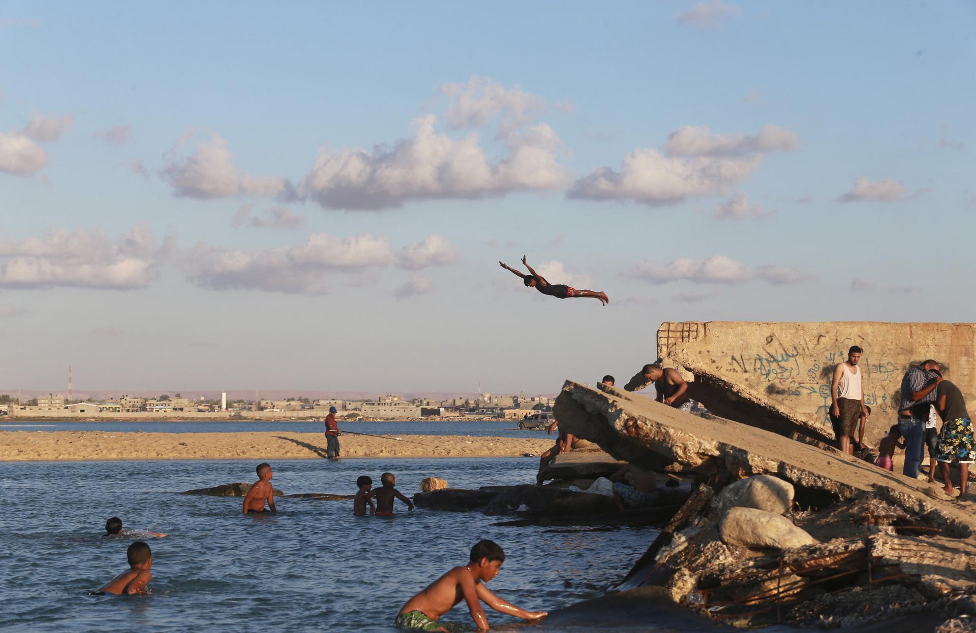 A beachgoer dives into the waters of the Mediterranean Sea, off the coast of Benghazi, Libya
