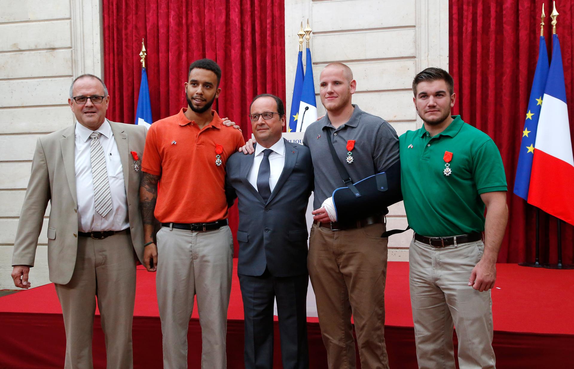 French President Francois Hollande (C) poses with British businessman Chris Norman (L), U.S. student Anthony Sadler (2ndL), U.S. Airman First Class Spencer Stone (2ndR) and U.S. National Guardsman Alek Skarlatos (R) during a ceremony at the Elysee Palace