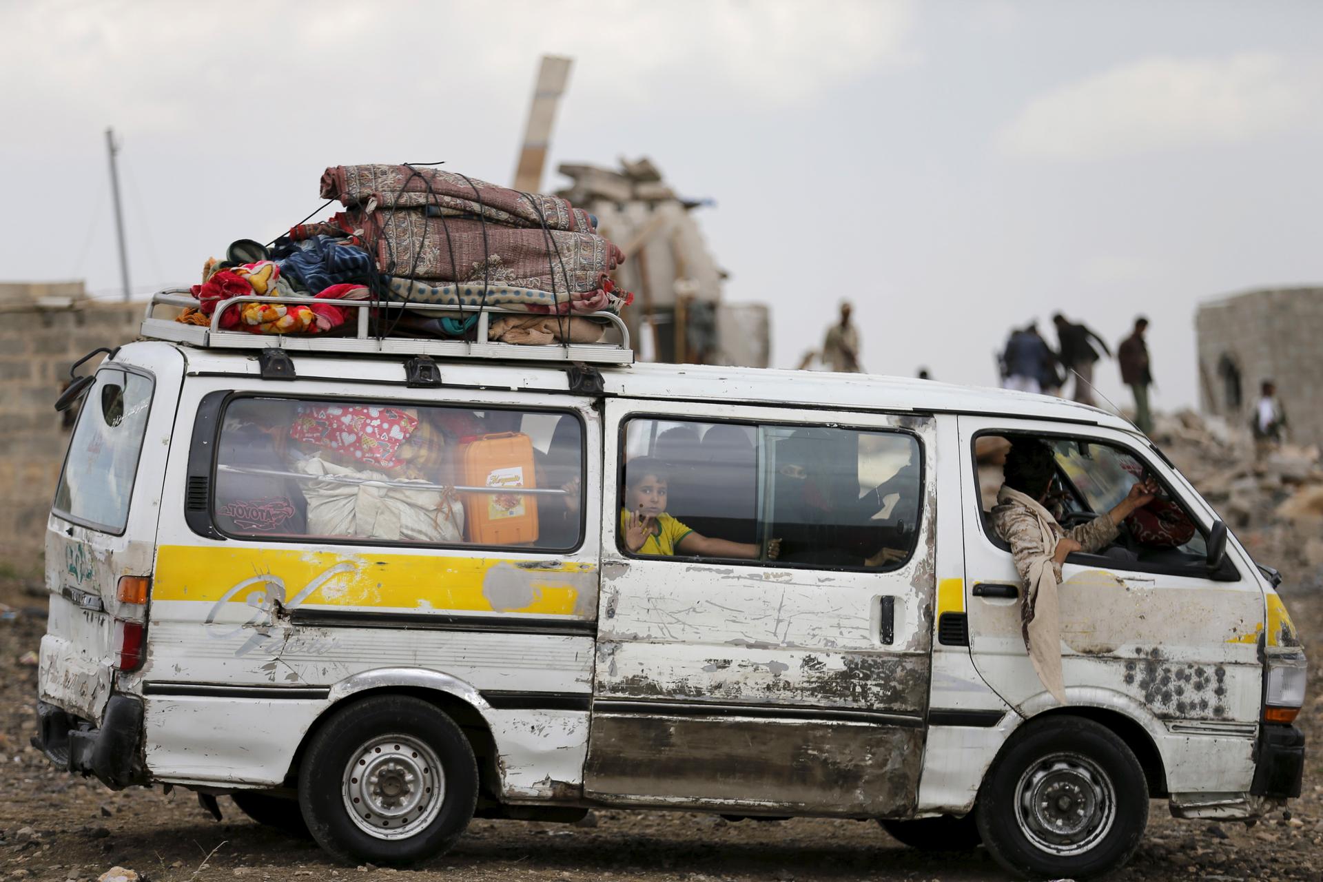 People ride a van as they flee their house near the site of a Saudi-led air strike in Yemen's capital Sanaa August 26, 2015.