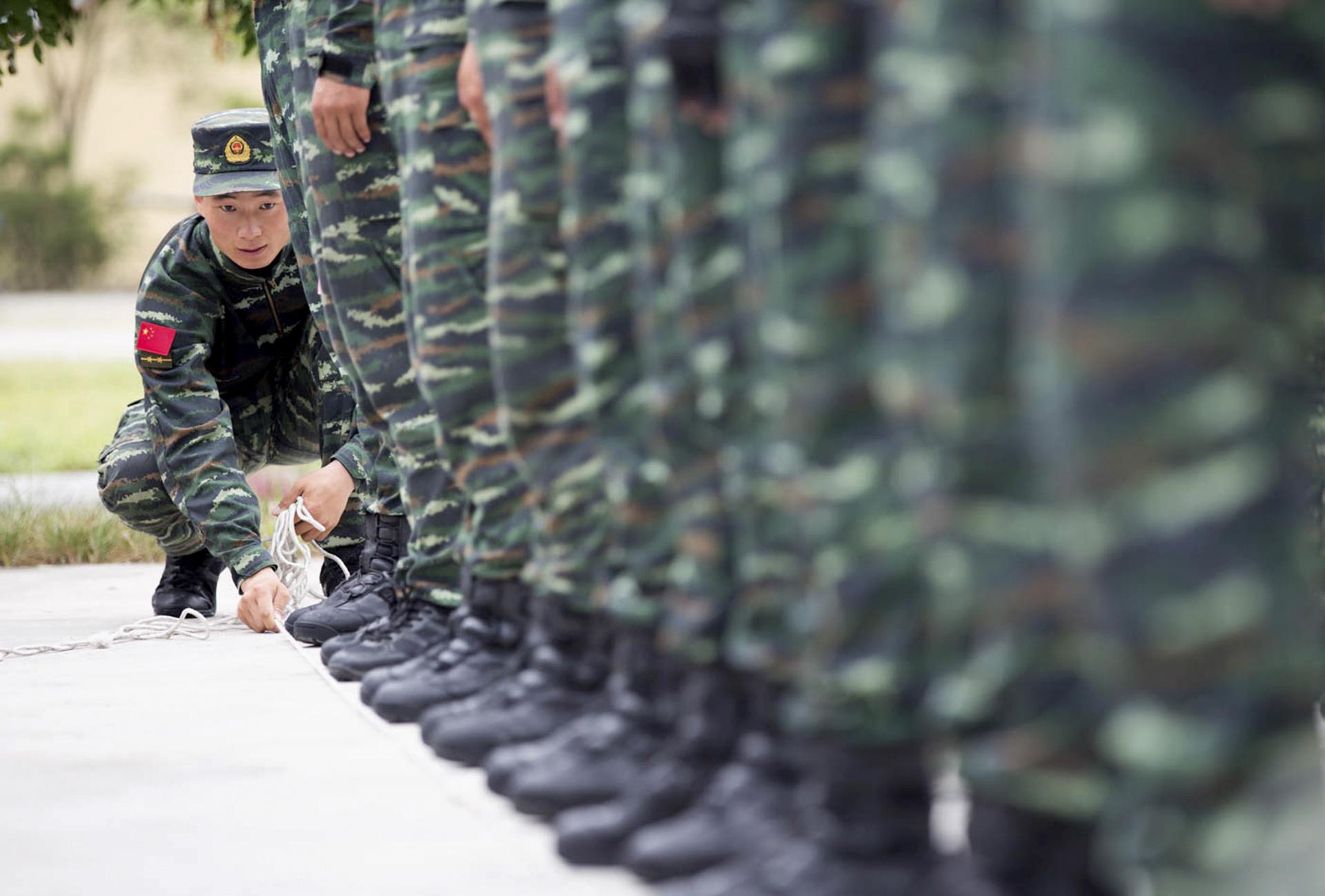 A soldier from China's People's Liberation Army uses a rope to line up other soldiers during a training session for a military parade to mark the 70th anniversary of the end of World War Two, at a military base in Beijing, China, September 1, 2015.