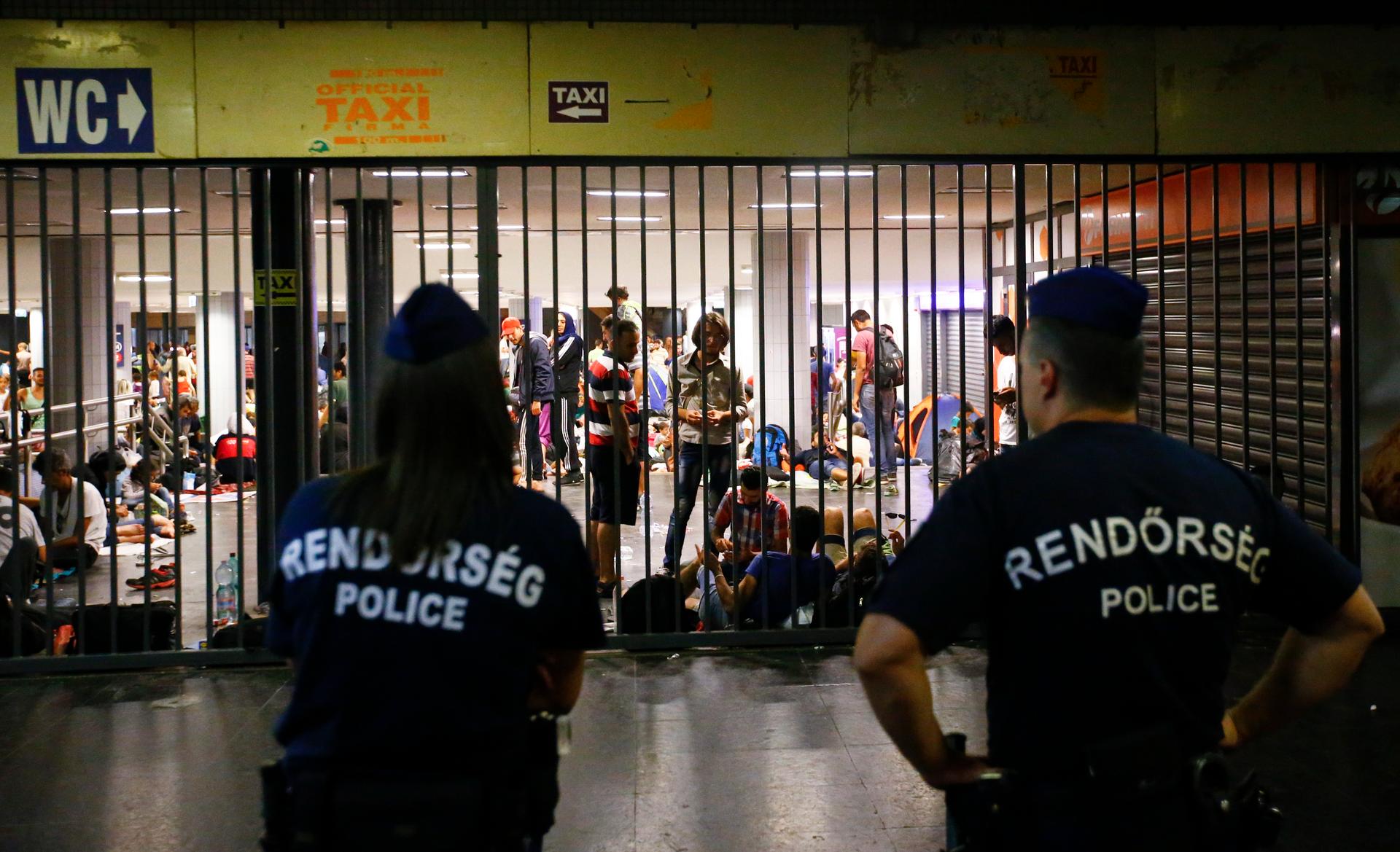 Hungarian police guard refugees at a makeshift camp in an underground station near the Keleti train station in Budapest, Hungary September 2, 2015.