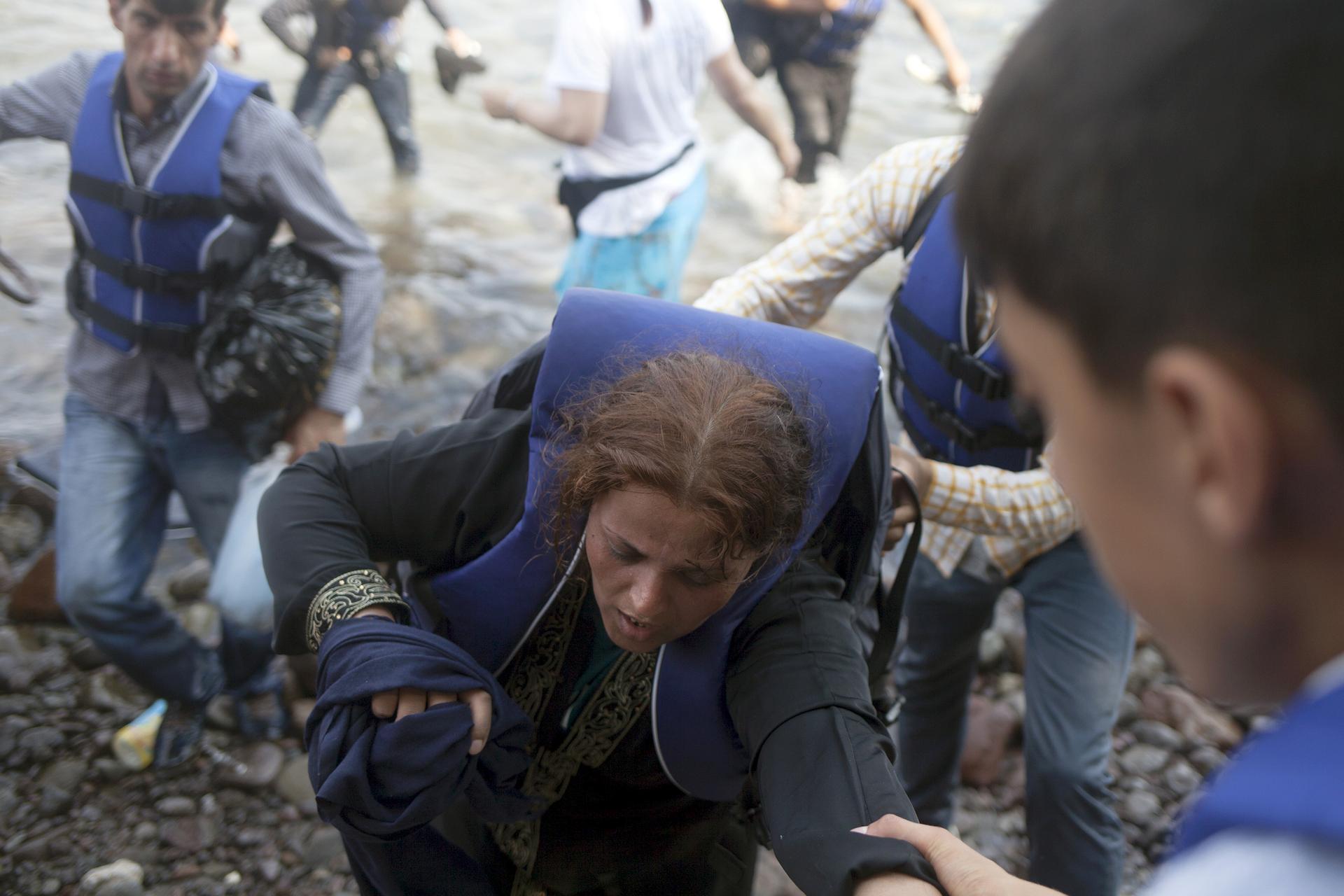 A Syrian refugee is helped moments after arriving on a dinghy on the Greek island of Lesbos September 3, 2015.
