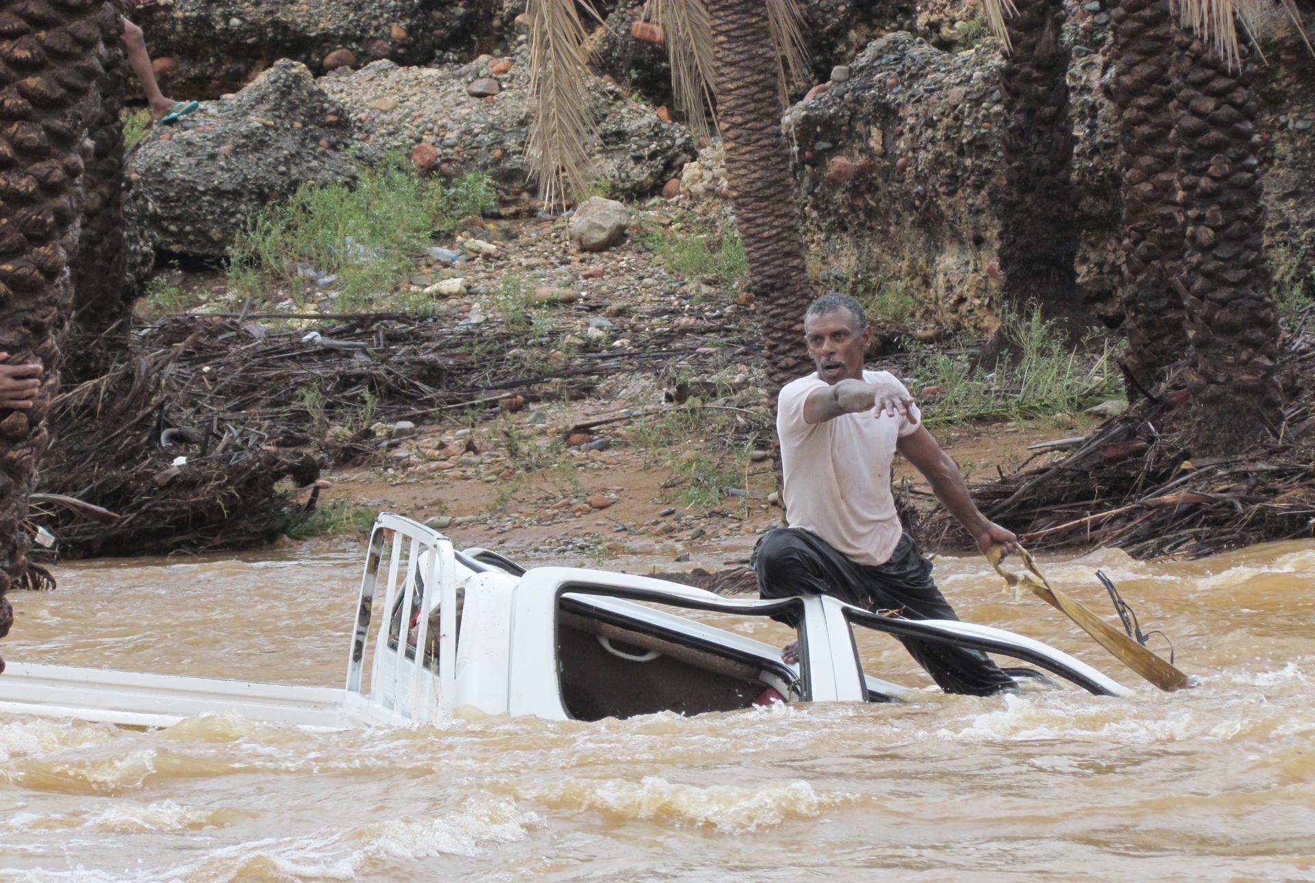 A man gestures as he tries to save a vehicle swept away by flood waters in Yemen's island of Socotra November 2, 2015. 