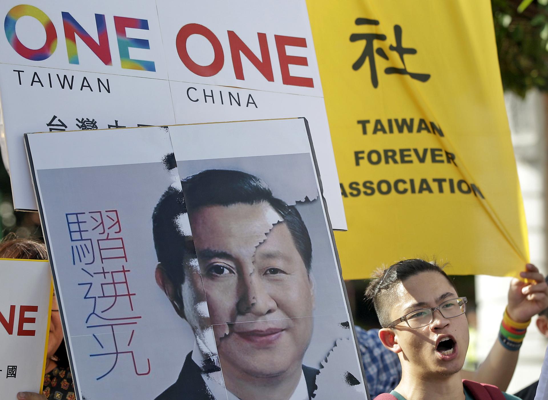 An activist holds a placard showing the merged faces of Taiwan's President Ma Ying-jeou and China's President Xi Jinping, to protest against the upcoming Singapore summit meeting between the two leaders.