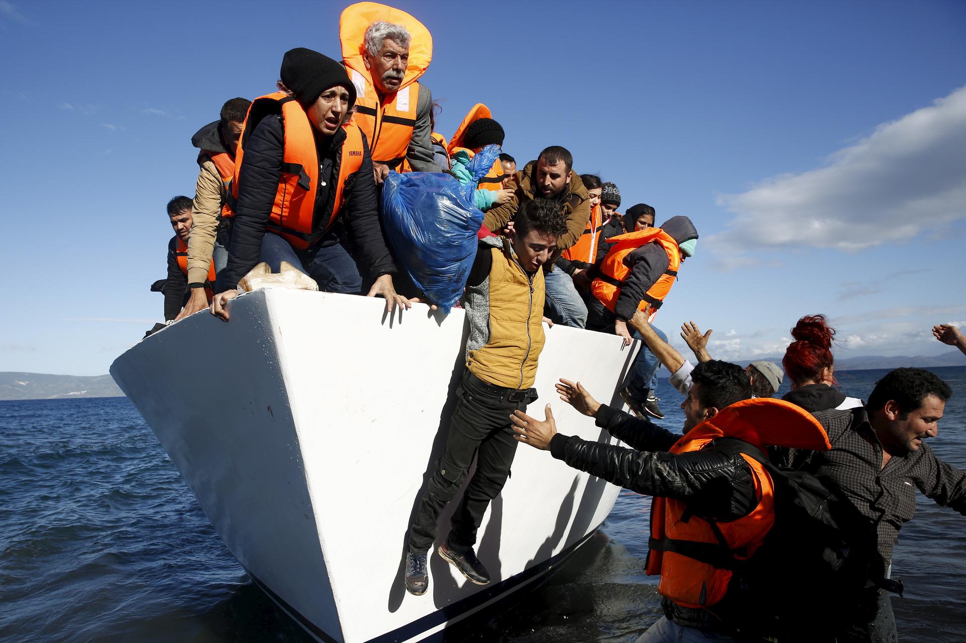 Refugees and migrants jump off a boat as they arrive on the Greek island of Lesbos, November 26, 2015.