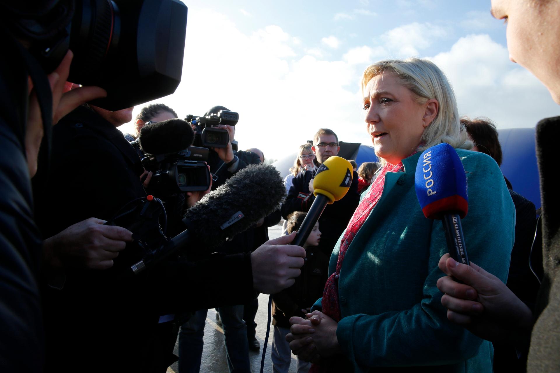 Marine Le Pen, French National Front political party leader and candidate for the National Front in the Nord-Pas-de-Calais-Picardie region, is surrounded by media as she campaigns for the upcoming regional elections