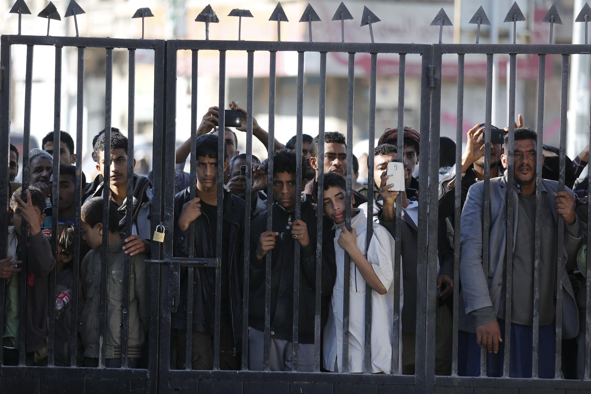 People look through a gate bars in Sanaa 