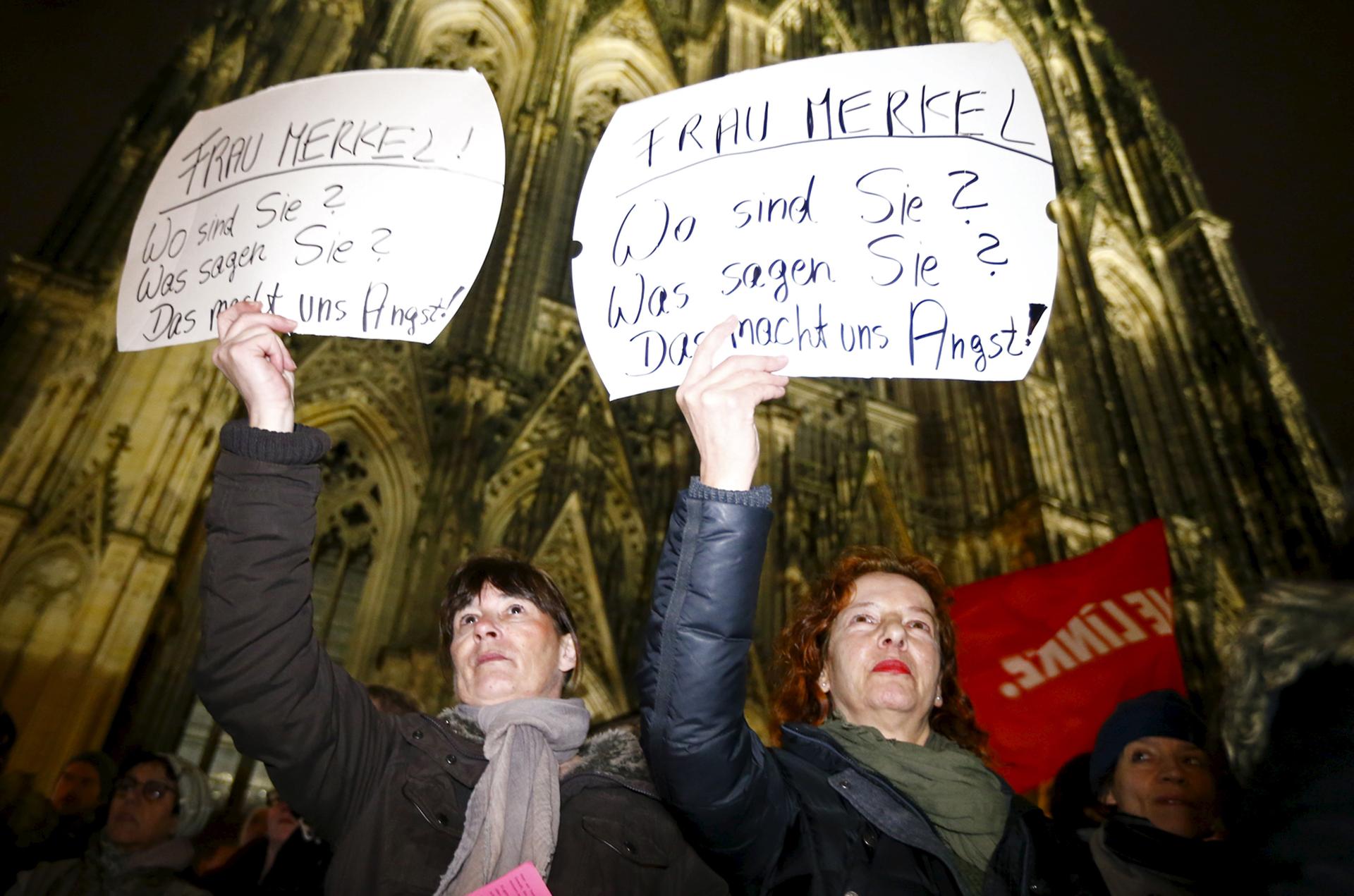 Women hold up placards that read "Mrs. Merkel: Where are you? What are you saying? This worries us!" during a protest in front of the Cologne Cathedral, Germany, January 5, 2016.
