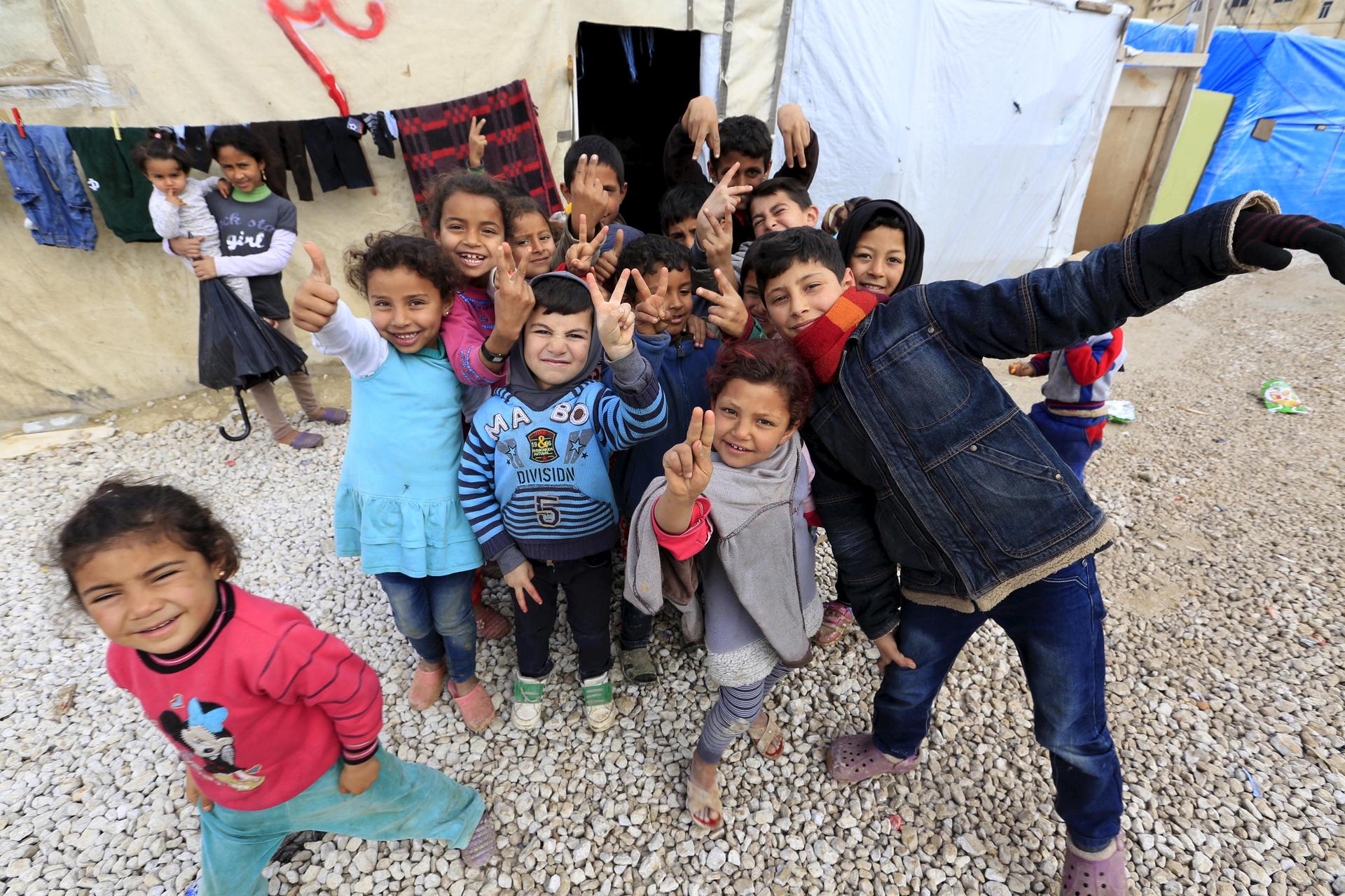 Children pose near tents inside an informal settlement for Syrian refugees in Bekaa Valley, Lebanon.