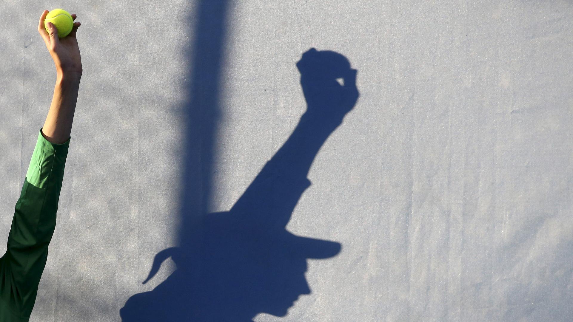 A ball boy is silhouetted as he holds up a tennis ball during a match at the Australian Open tennis tournament at Melbourne Park, Australia, January 18, 2016.