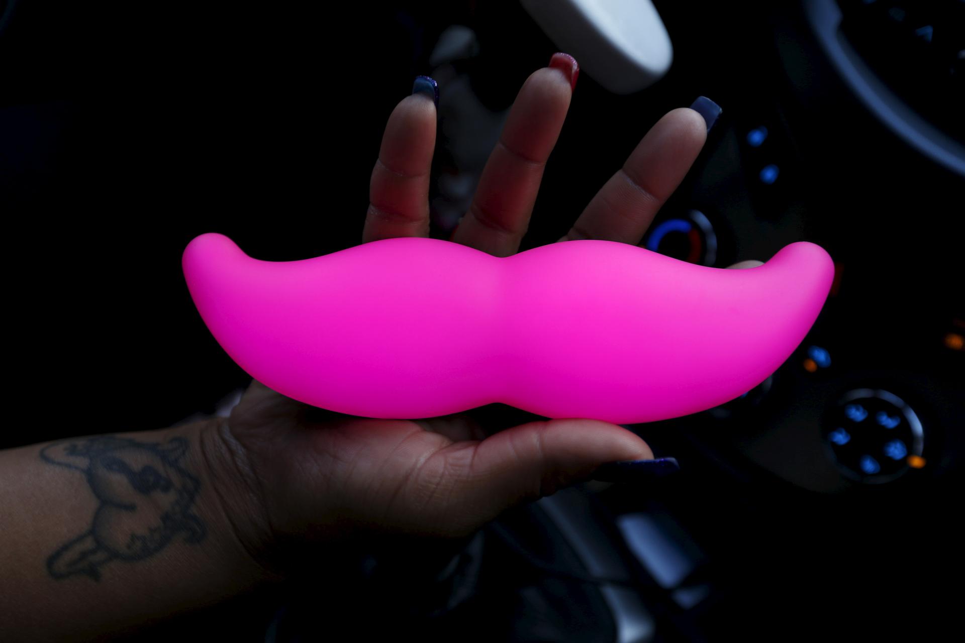 A woman holds a glow in the dark mustache 
