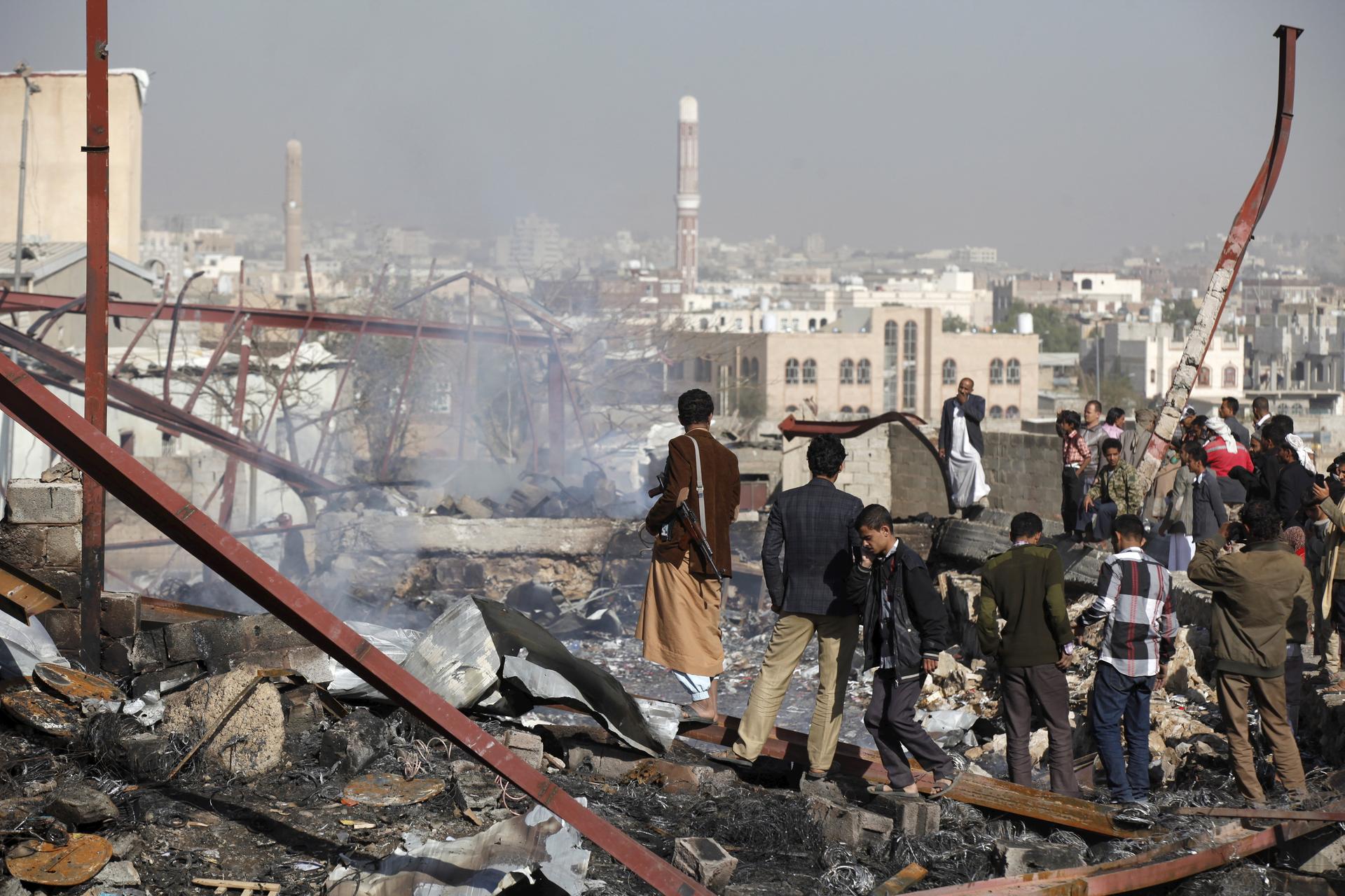 People stand on the rubble of an electronics warehouse store after a Saudi-led air strike destroyed it in Yemen's capital Sanaa