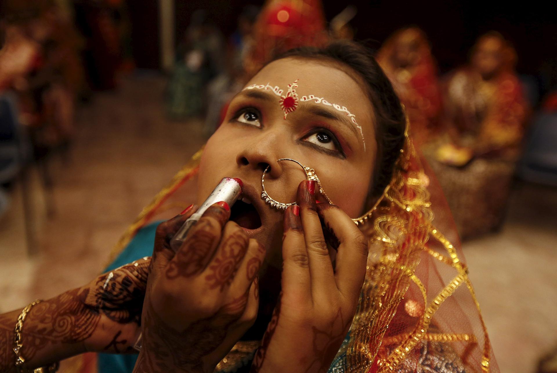 A bride gets her makeup done before her marriage ceremony.