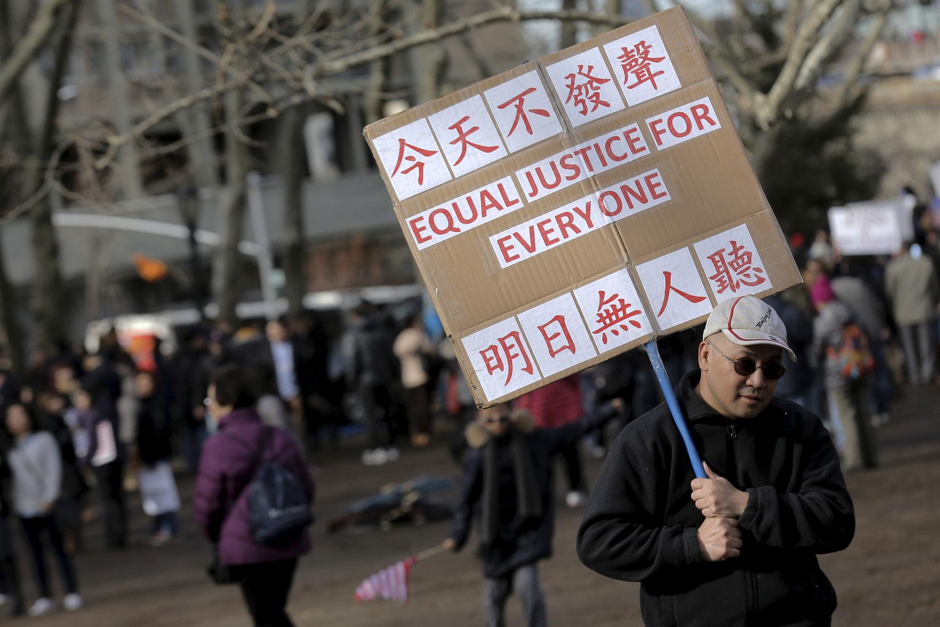 A man holds a sign that reads "All lives matter" in English and Chinese
