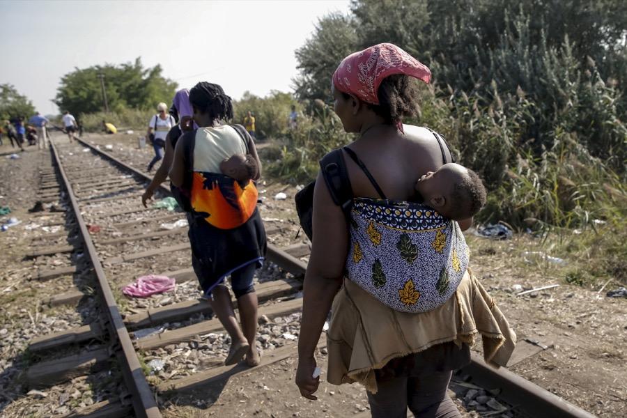 Migrants, hoping to cross into Hungary, walk with babies on their backs along a railway track outside the village of Horgos in Serbia, toward the border it shares with Hungary, on Aug. 31, 2015.