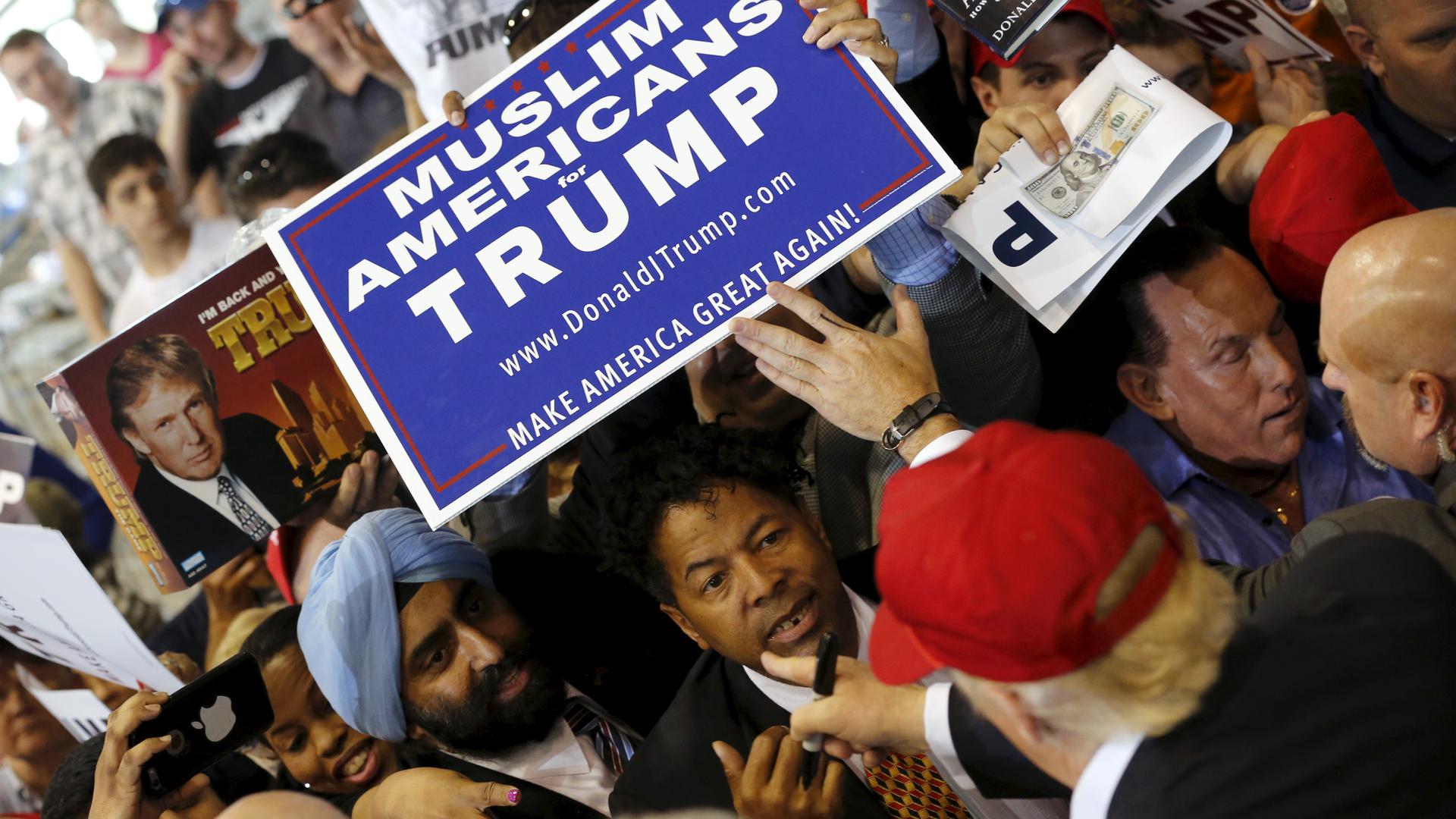 US Republican presidential candidate Donald Trump signs autographs for supporters holding a Muslim Americans for Trump sign after a rally in Harrington, Delaware April 22, 2016.