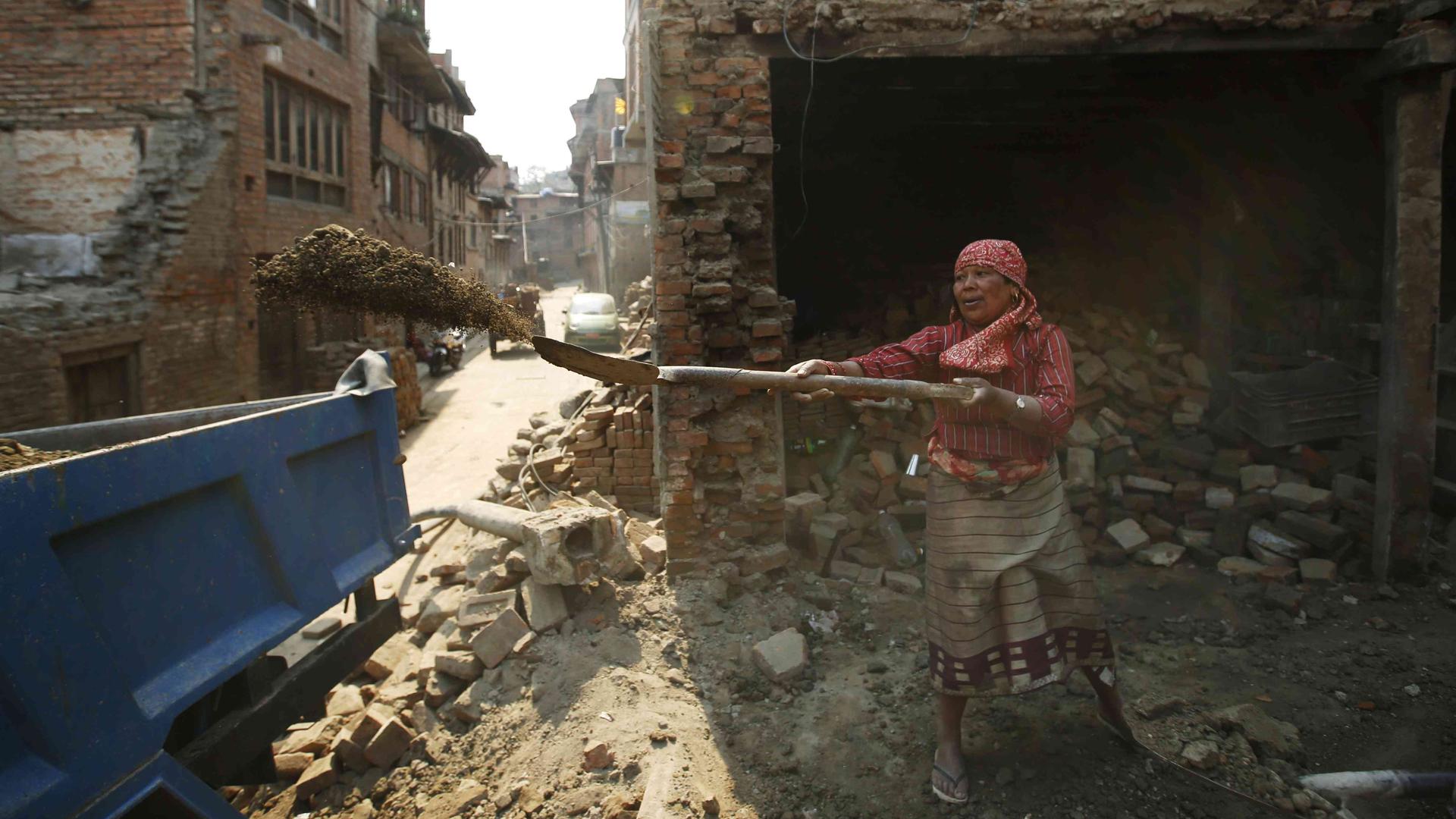 Woman with tool in front of damaged building