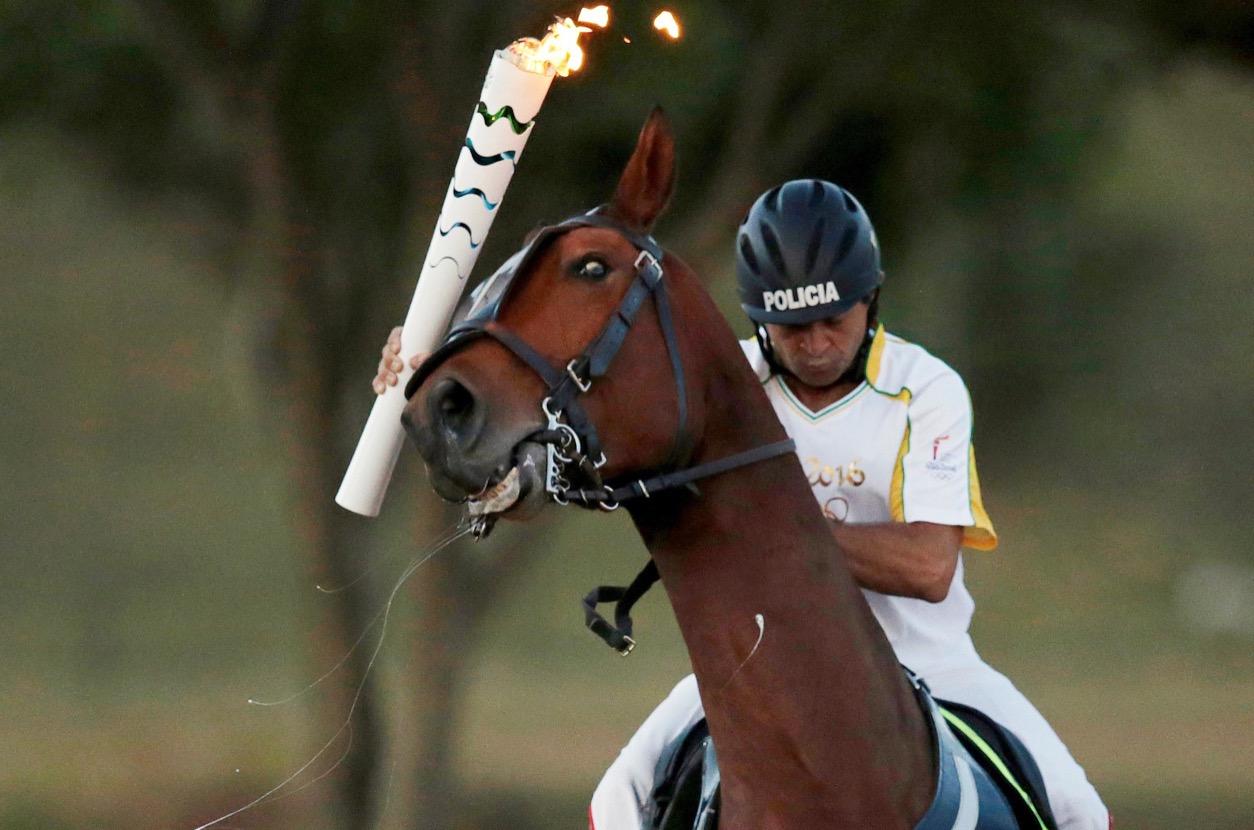 Brazil's Jose Batista holds the Olympic torch as he rides his horse during the torch relay in Brasilia on May 3.