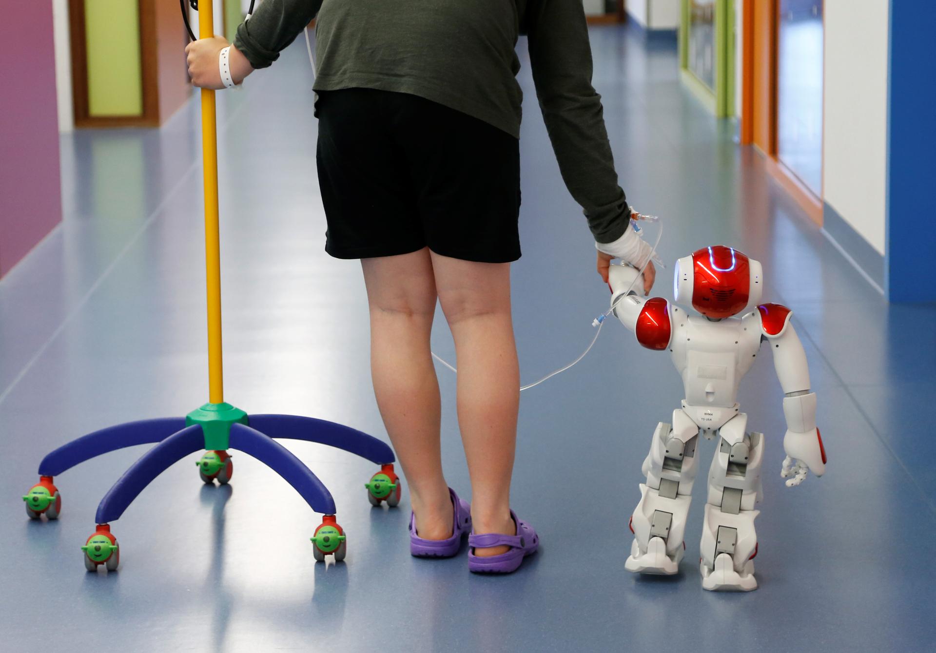 Belgian Ian Frejean, 11, walks with "Zora" the robot, a humanoid robot designed to entertain patients and to support care providers, at AZ Damiaan hospital in Ostend, Belgium June 16, 2016.
