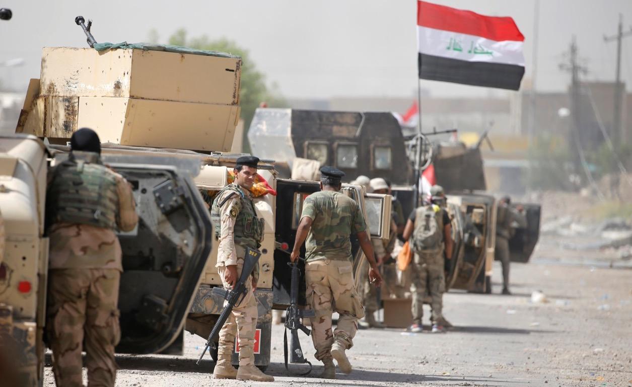 Iraqi army soldiers carry their weapons and the national flag in the center of Fallujah on June 17.