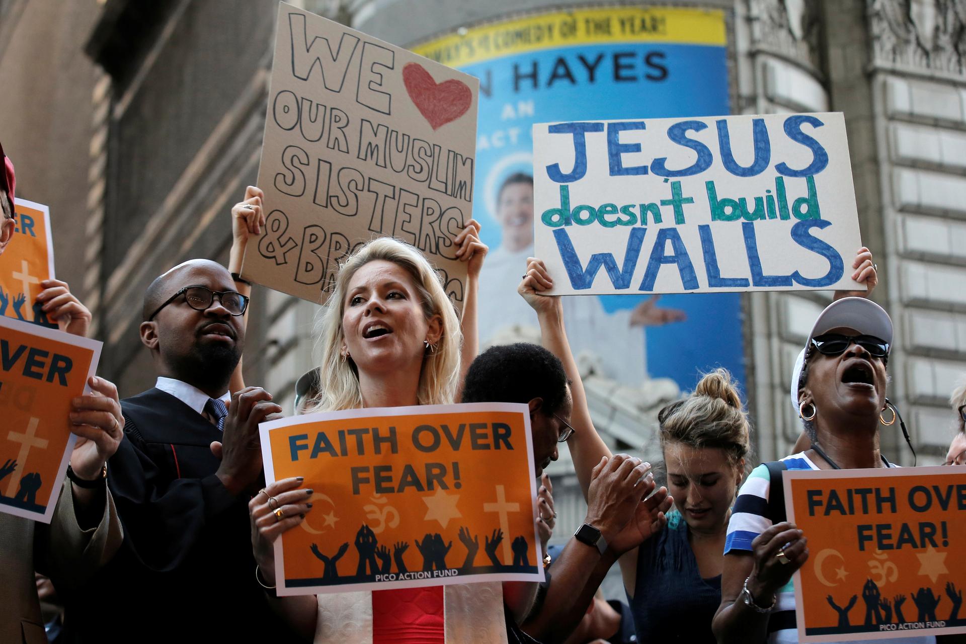 group of protesters, with signs "Jesus doesn't build walls" and "Faith over fear"