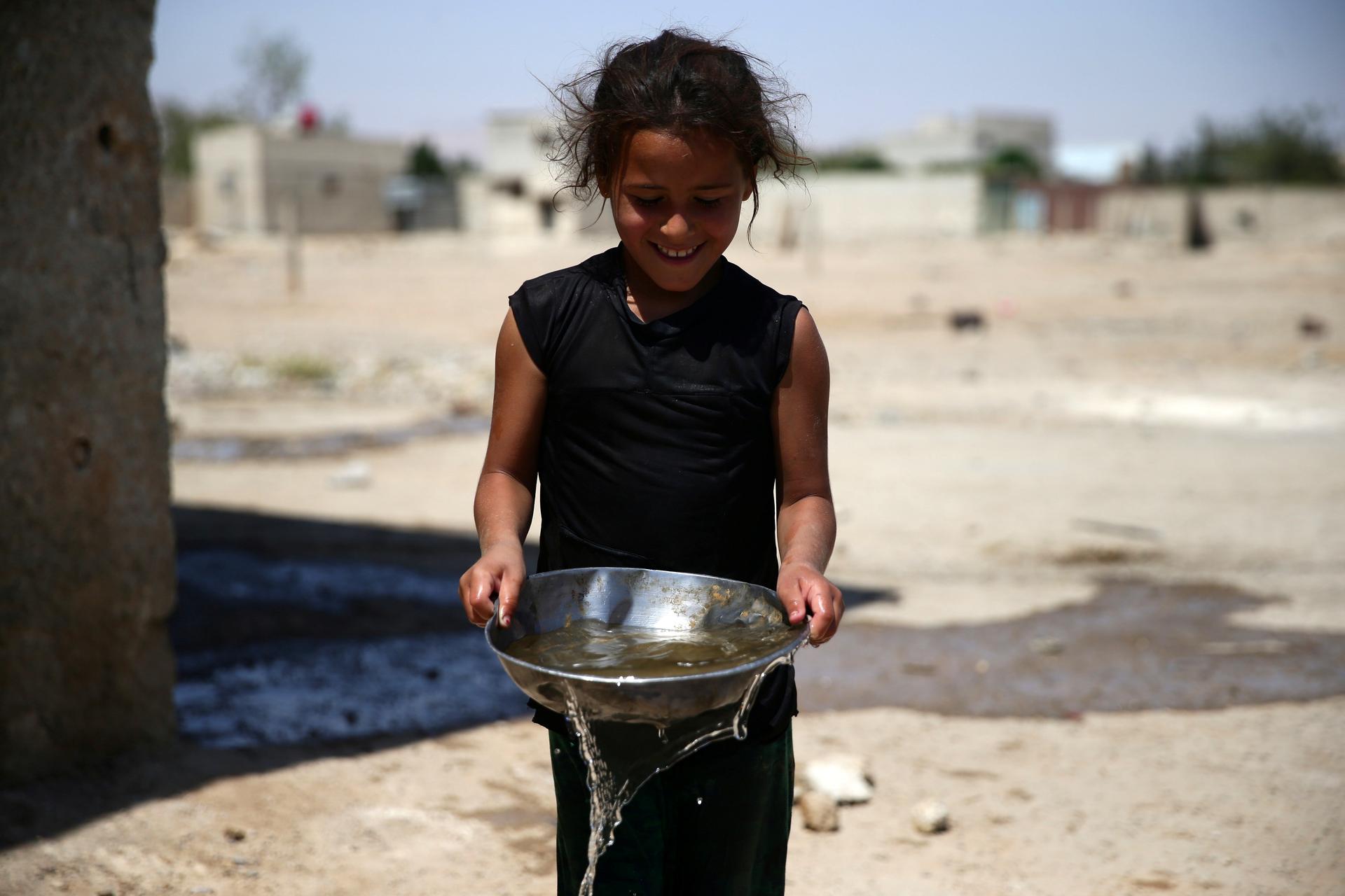 A girl carries a bowl filled with water, in the rebel held besieged town of Douma, eastern Damascus.