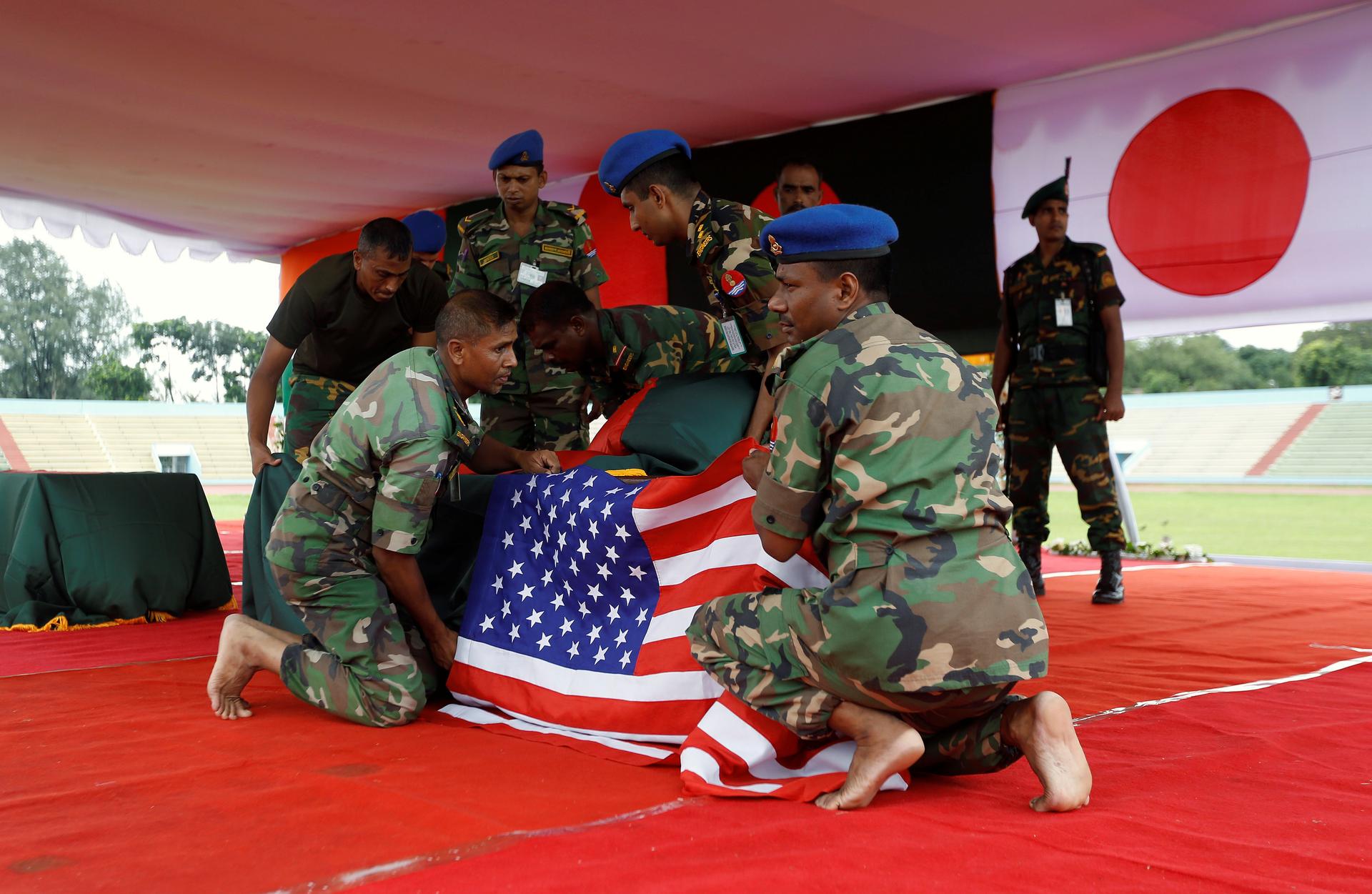 Bangladeshi army personnel place a U.S. flag on a coffin of a victim who was killed in the attack on the Holey Artisan Bakery and the O'Kitchen Restaurant, during a memorial ceremony in Dhaka, Bangladesh, July 4, 2016. REUTERS/Adnan Abidi