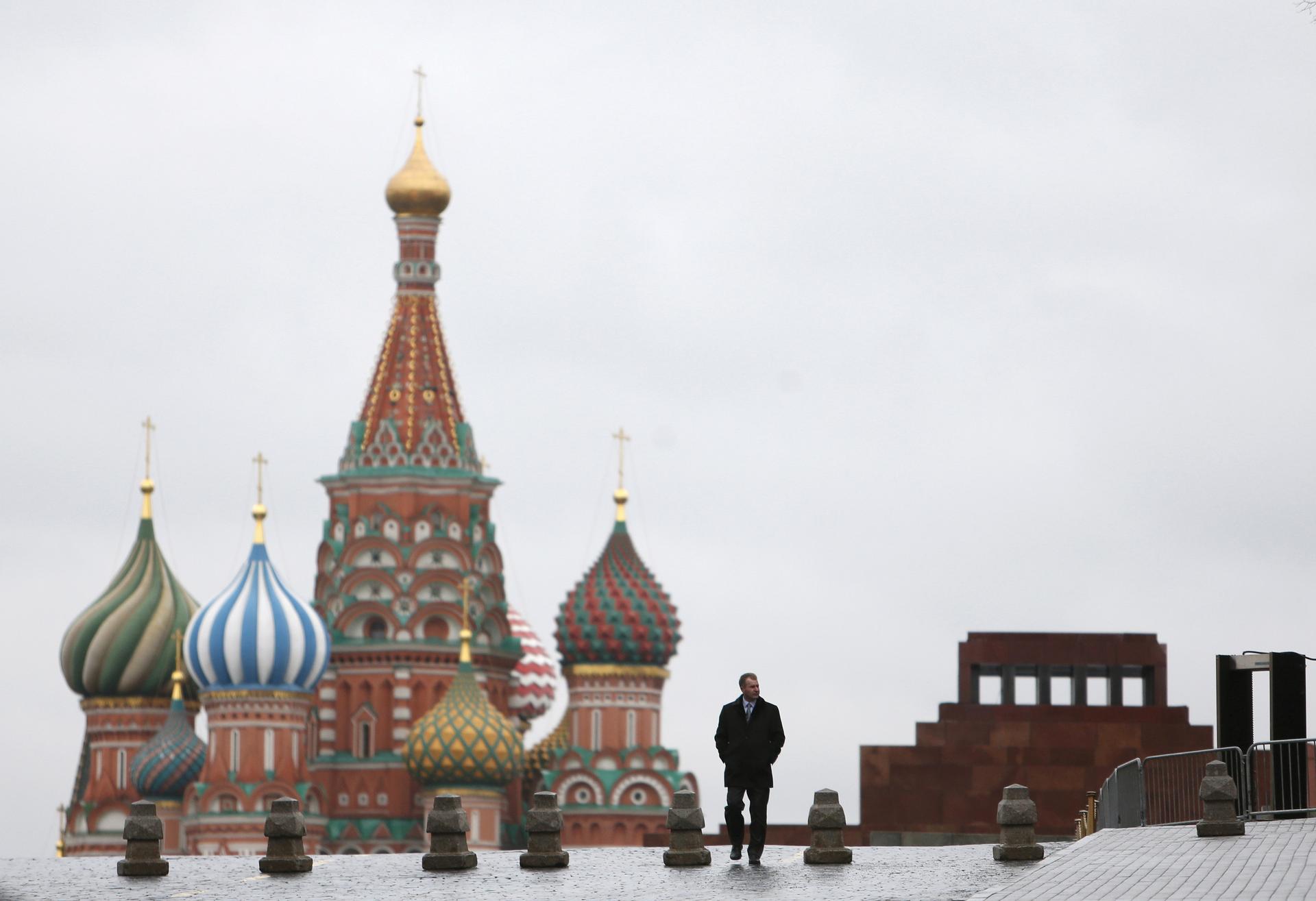 A man walks along Red Square, with the mausoleum of Vladimir Lenin and St. Basil's Cathedral in the background, in central Moscow, Russia.