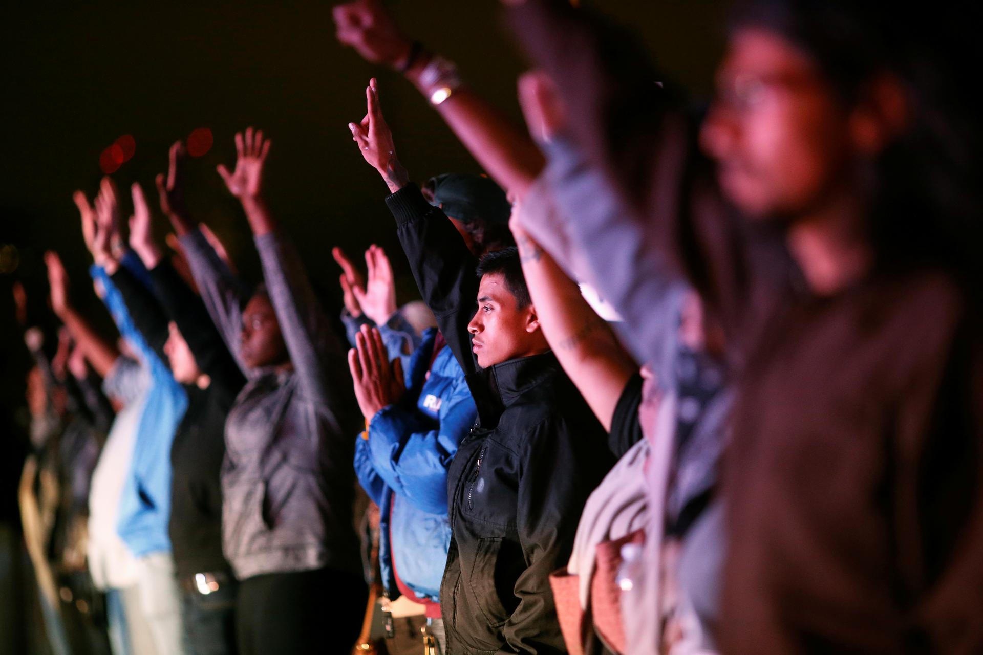 Demonstrators raise their hands toward a line of police officers on Highway 880 during a protest against the police shootings that lead to two deaths in Louisiana and Minnesota, respectively, in Oakland, California, U.S.