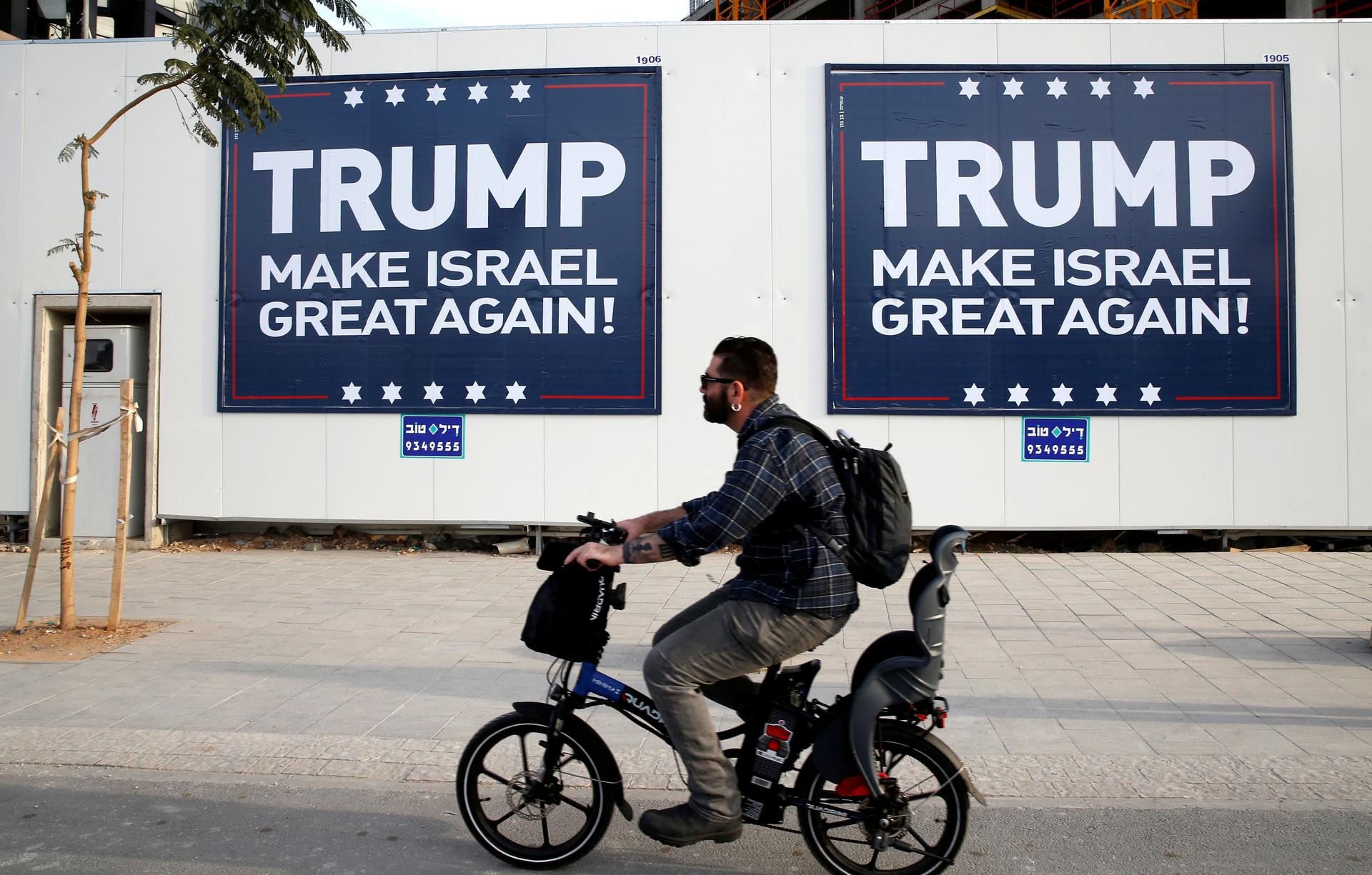 A man cycles past signs bearing the name of U.S. President-elect Republican Donald Trump in Tel Aviv, Israel November 14, 2016.