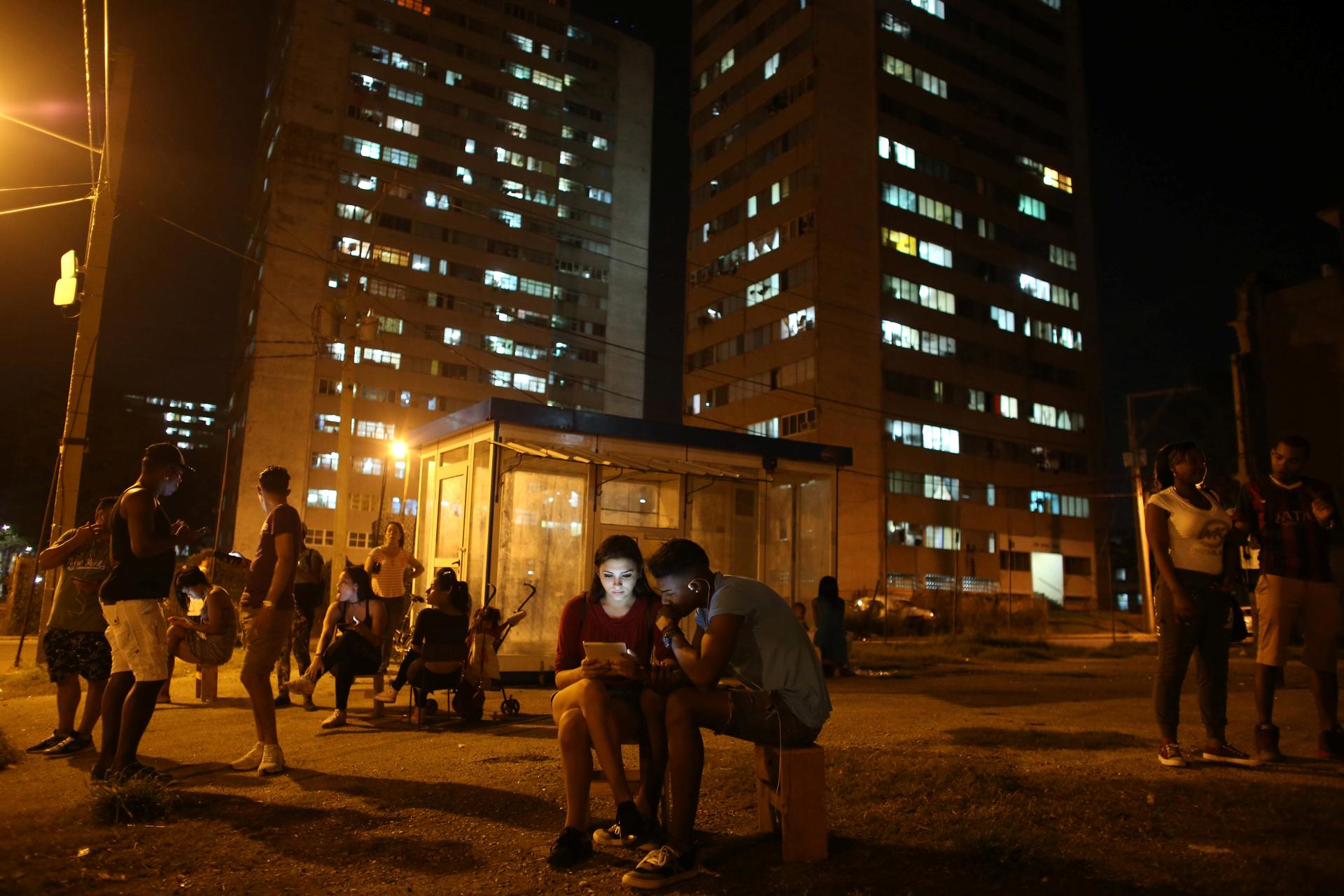 Carolina Gutierrez (center L), 17, and Neuil Valdez, 18, use mobile phones to connect to the internet at a hotspot in downtown Havana, Cuba, December 12, 2016.