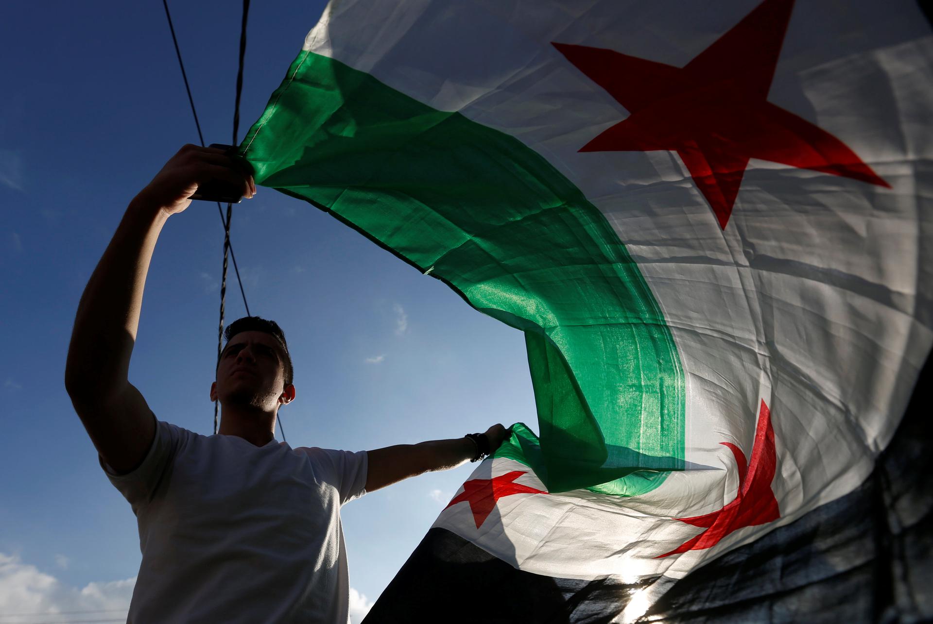 A protester holds a Syrian opposition flag during a sit-in against the Syrian regime, in front of the UNDP office in Amman, Jordan.
