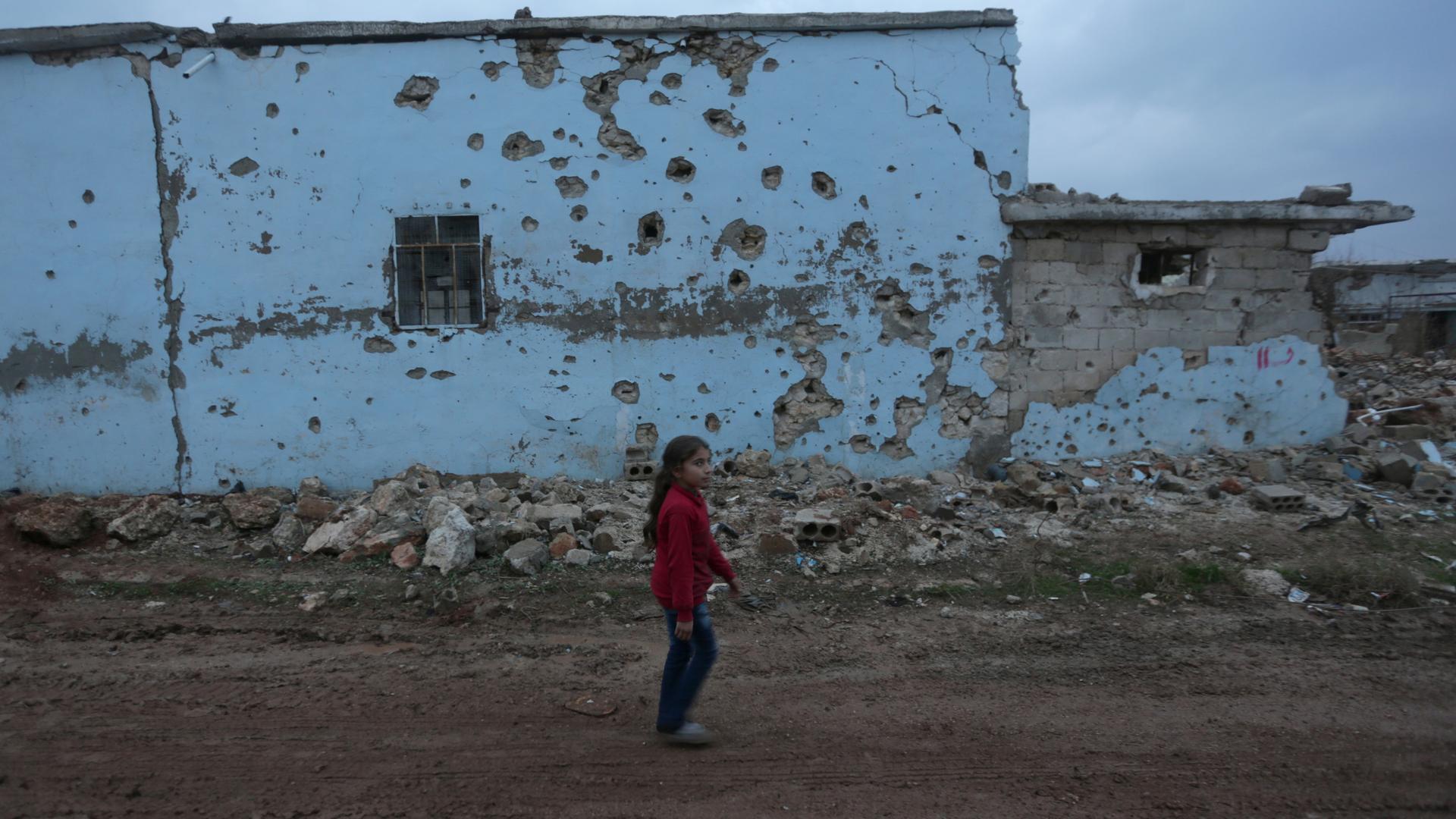 A girl walks near a damaged house in northern Syria, Tuesday. The civil war in Syria is almost six years old.