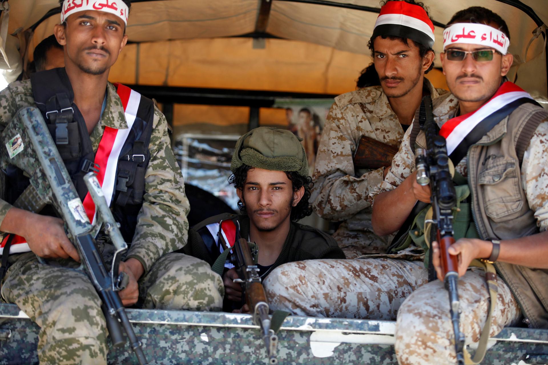 Newly recruited Houthi fighters ride on the back of a pick-up truck