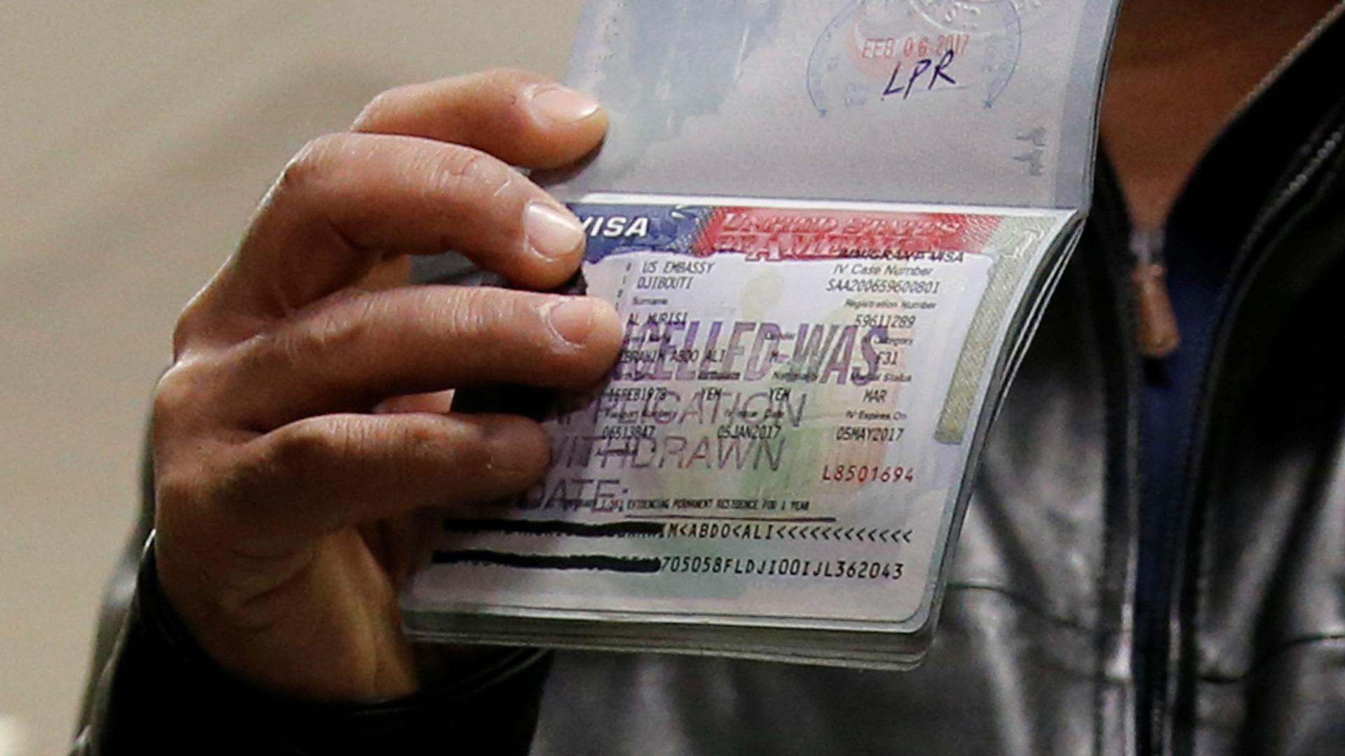 A Yemeni national who was denied entry into the US after President Donald Trump's first immigration and refugee visa ban shows the canceled visa in a passport, at Washington Dulles International Airport in Chantilly, Virginia, Feb. 6, 2017.