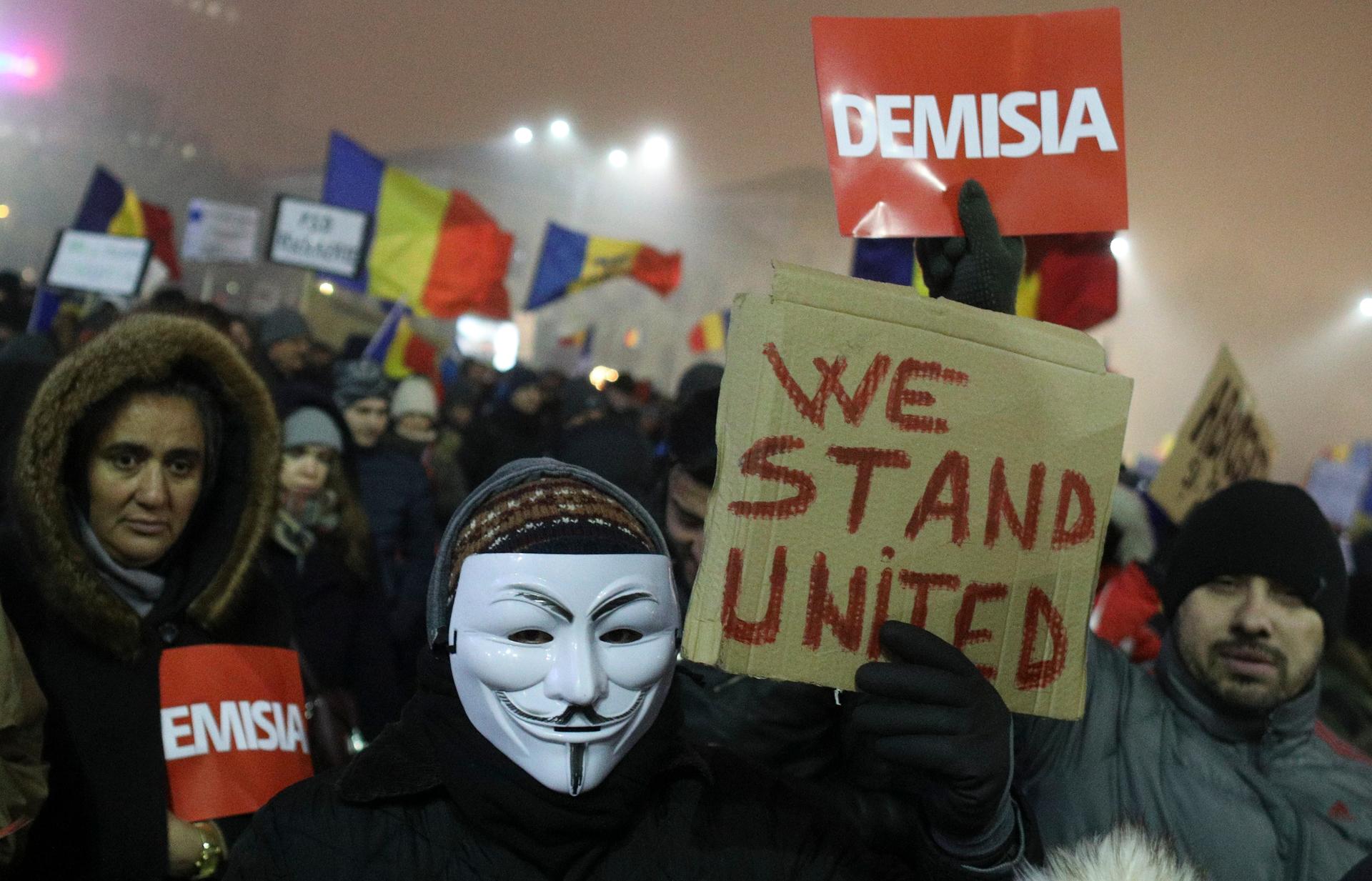 A Romanian holds a sign that reads "we stand united" during a demonstration of thousands against the  government in Bucharest, Romania, Feb. 6, 2017.