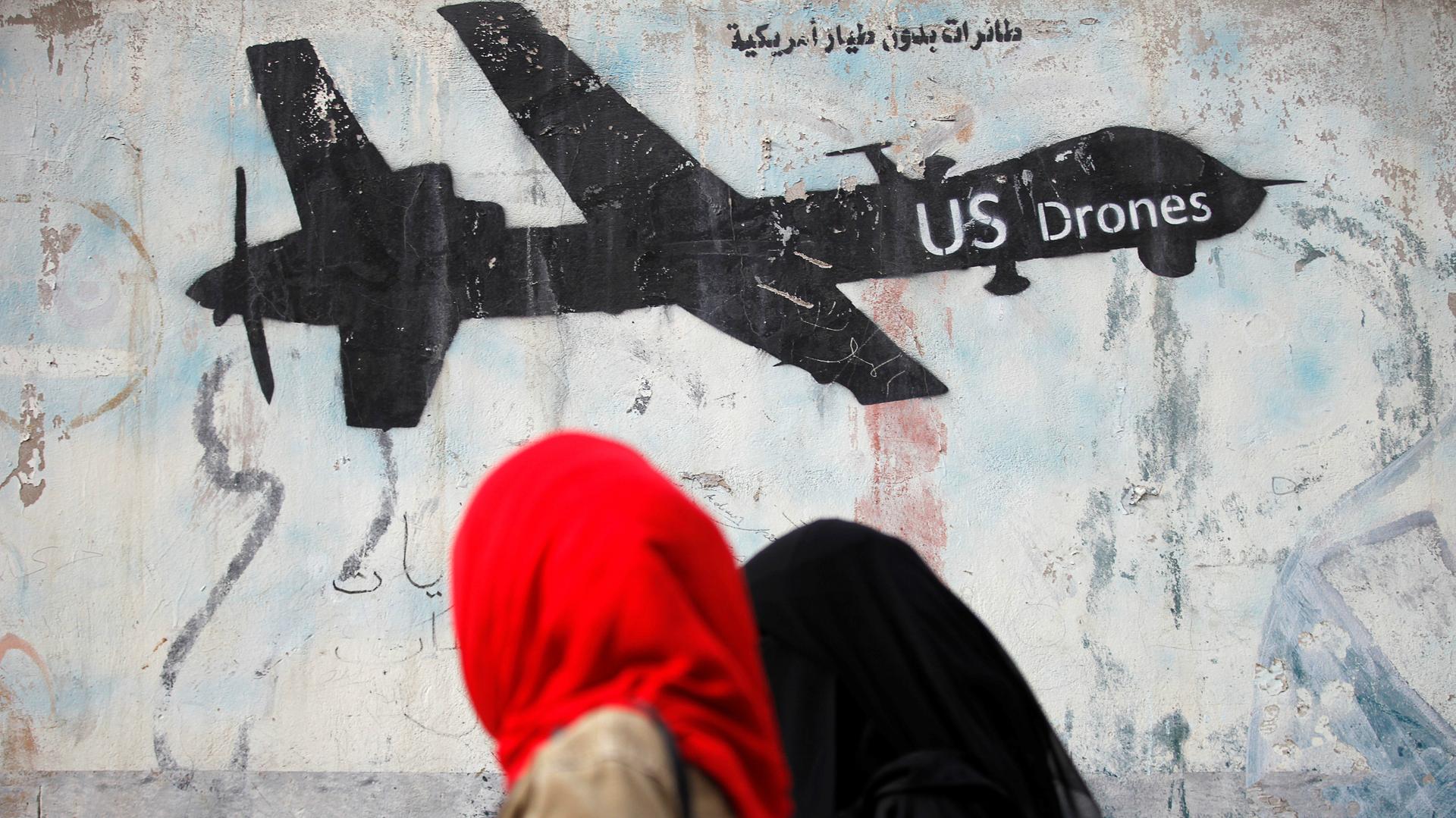 Women walk past graffiti denouncing strikes by US drones in Yemen, painted on a wall in Sanaa, Yemen, Feb. 6, 2017.