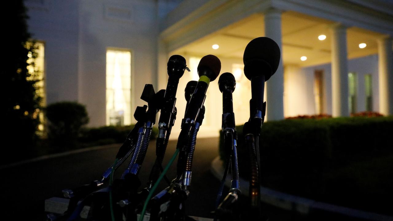 Microphones remain at the ready as night falls on the entrance of the West Wing