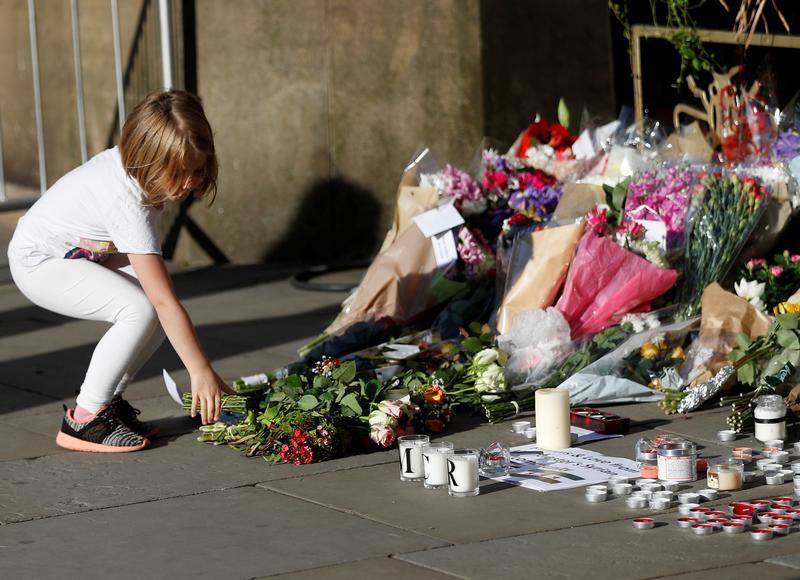 A girl leaves flowers for the victims of an attack on concert goers at Manchester Arena.