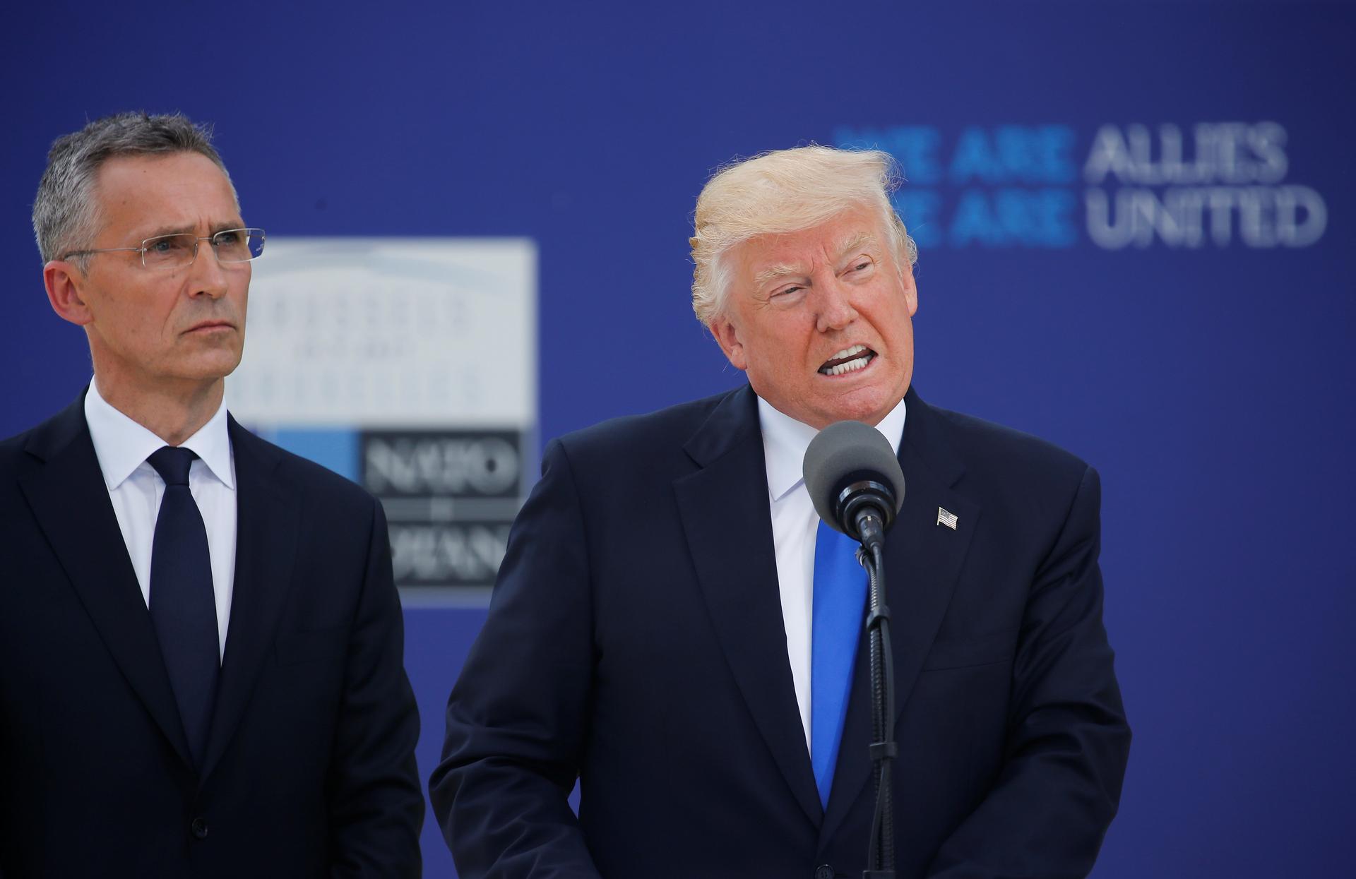 President Donald Trump speaks beside NATO Secretary General Jens Stoltenberg at the start of the NATO summit.